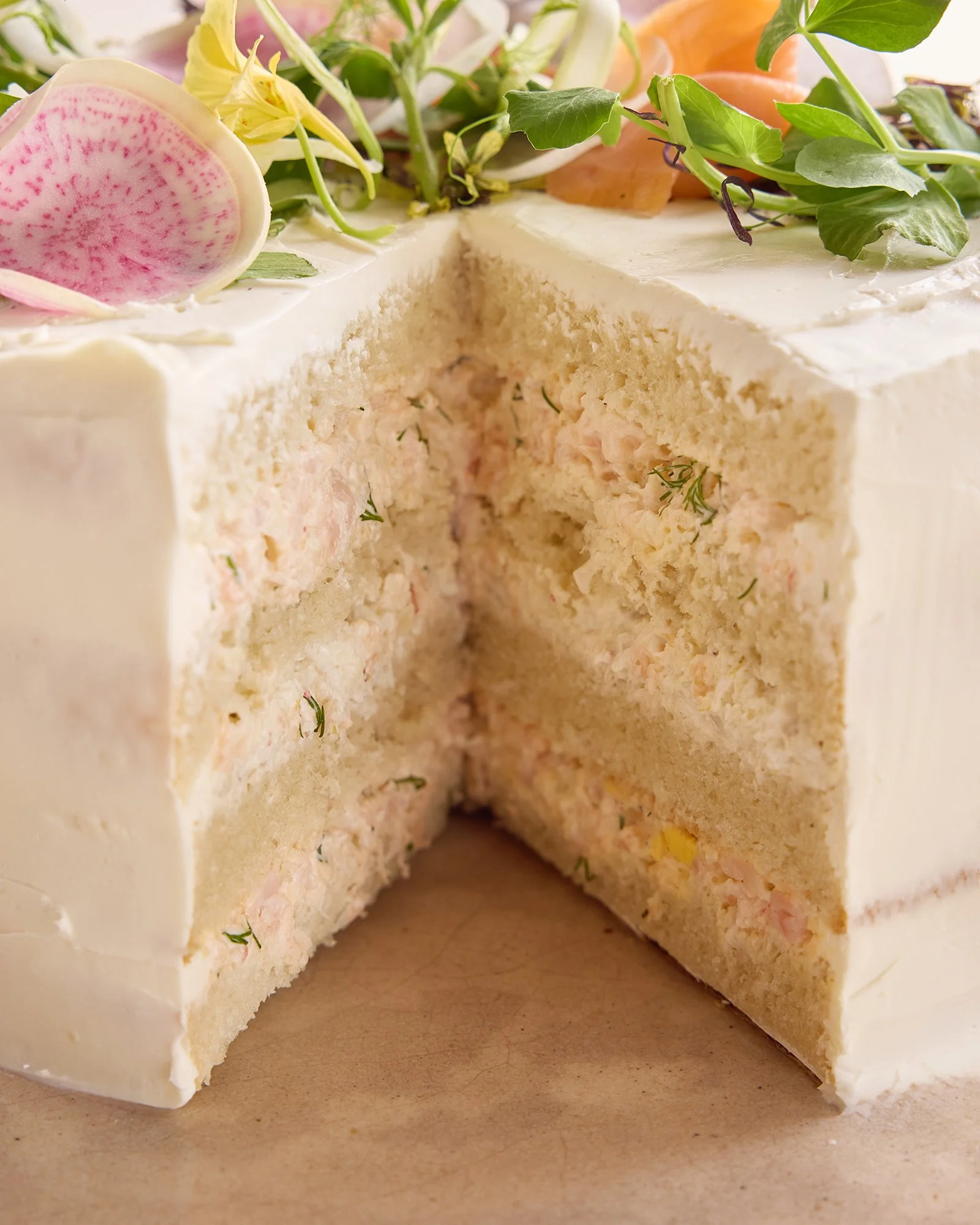 Cross-section of a layered seafood or chicken salad sandwich with white bread, filled with a creamy mixture that includes small pieces of seafood or chicken, garnished with herbs.