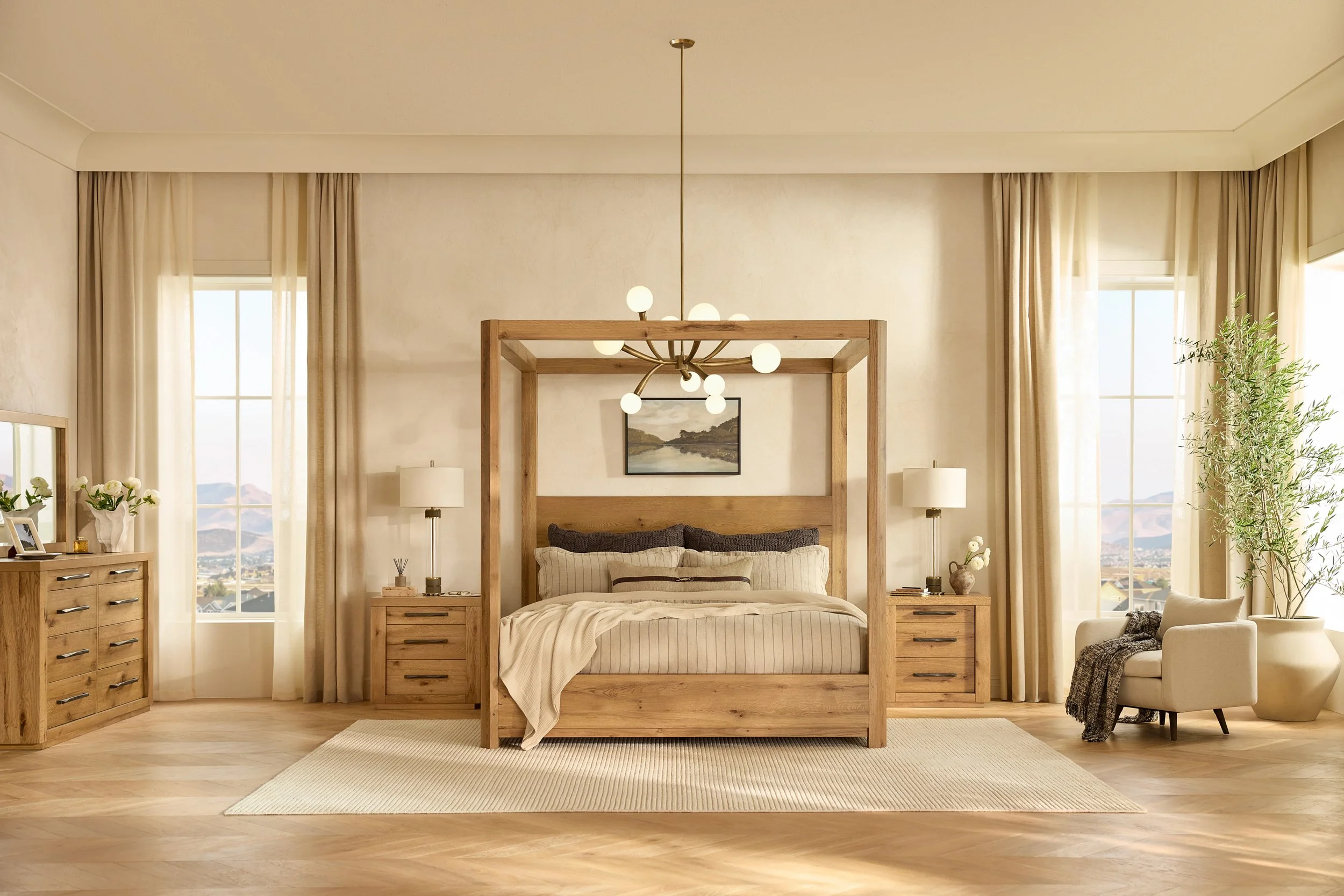 A modern bedroom with a wooden bed frame, tan bedding, two nightstands with lamps, large windows with cream curtains, and a chandelier, with a landscape painting on the wall.