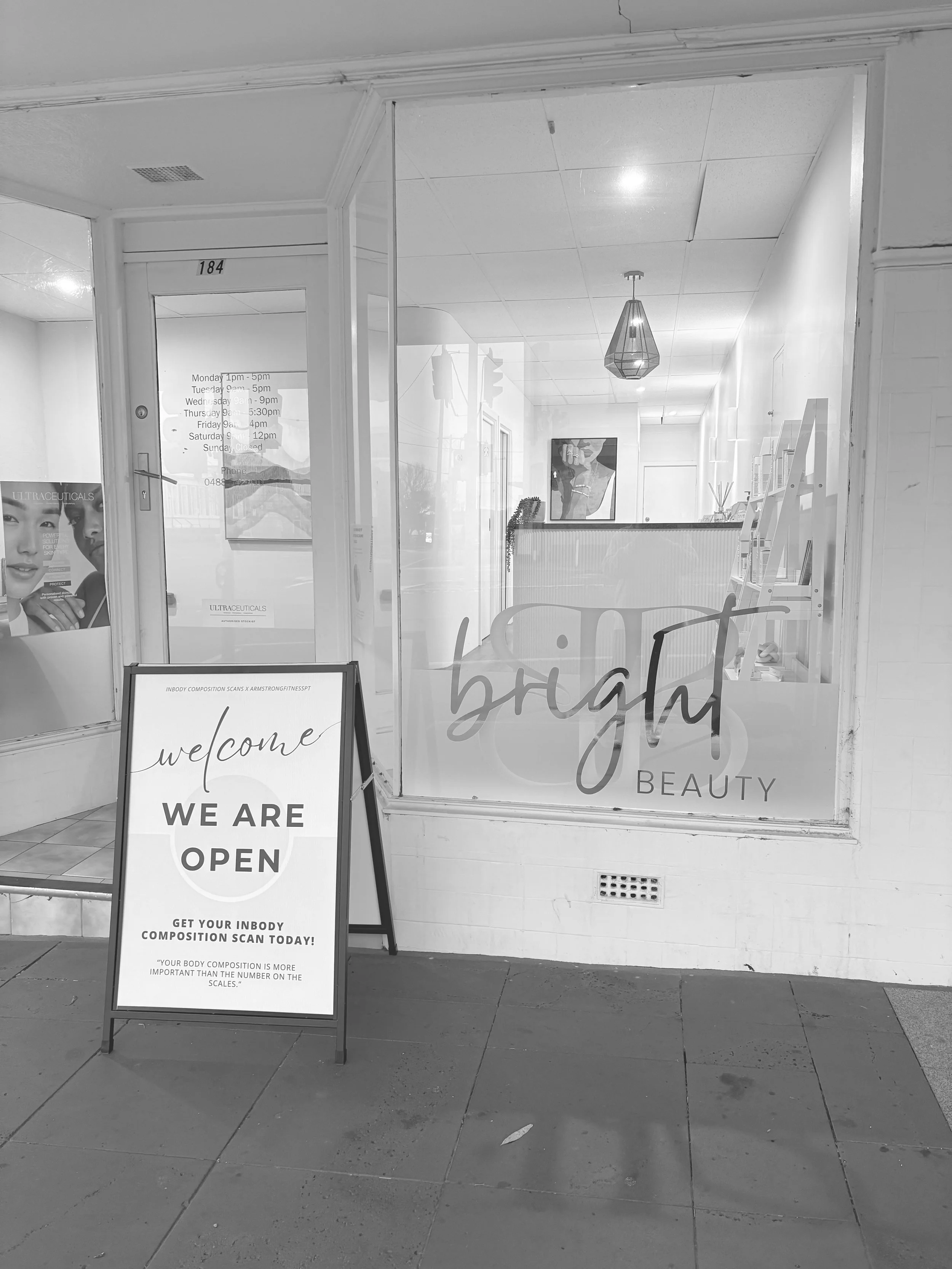 Storefront entrance with large window displaying the words 'bright beauty'. A sign outside indicates the business is open with the message 'we are open' and encourages customers to get an inbody body composition scan.