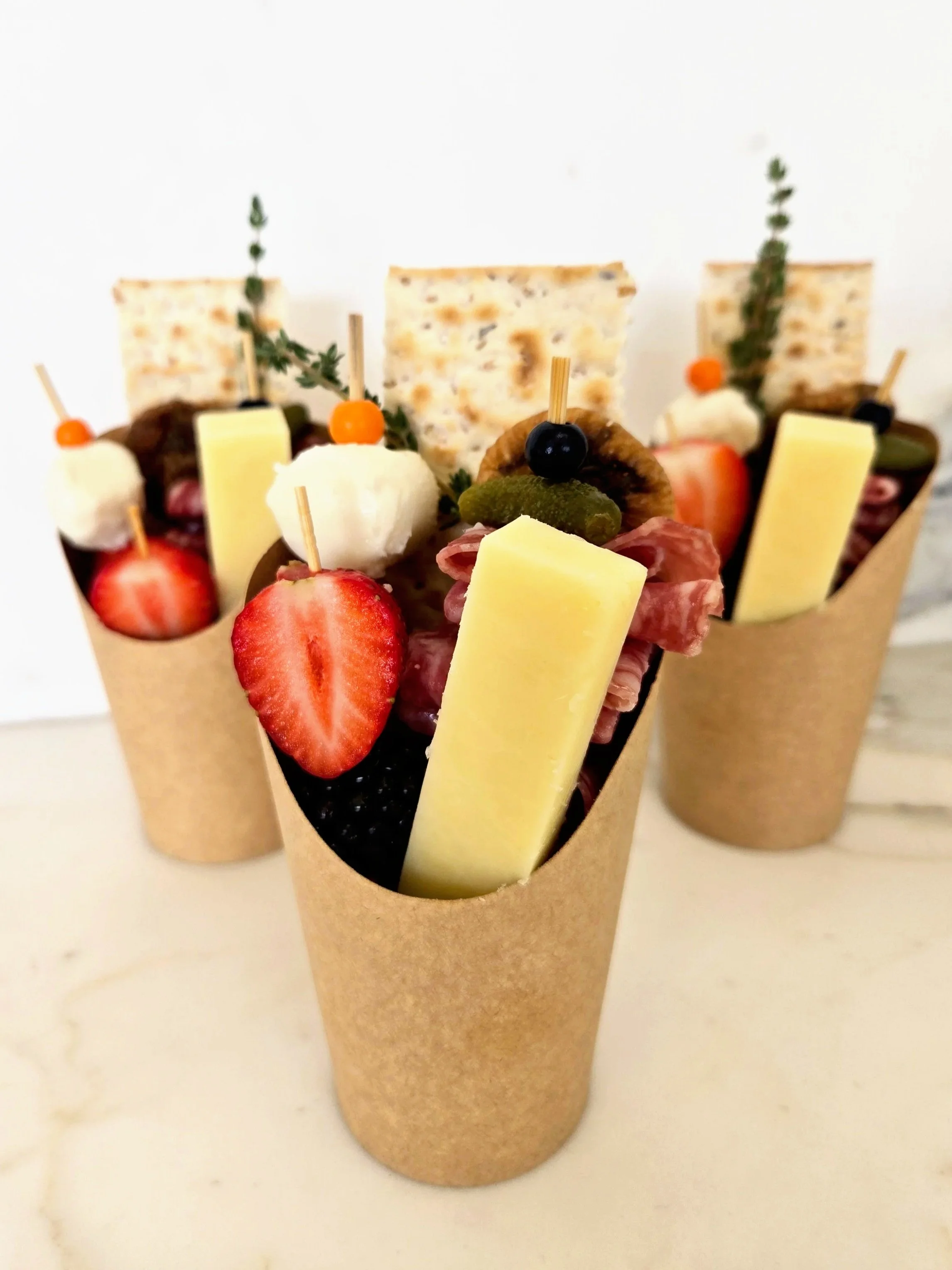 St. Uguzo individual paper cups filled with assorted cheeses, cured meats, fresh fruit, and crackers for small and large gatherings. Serving Ventura County, Santa Barbara County, and Northern Los Angeles County.