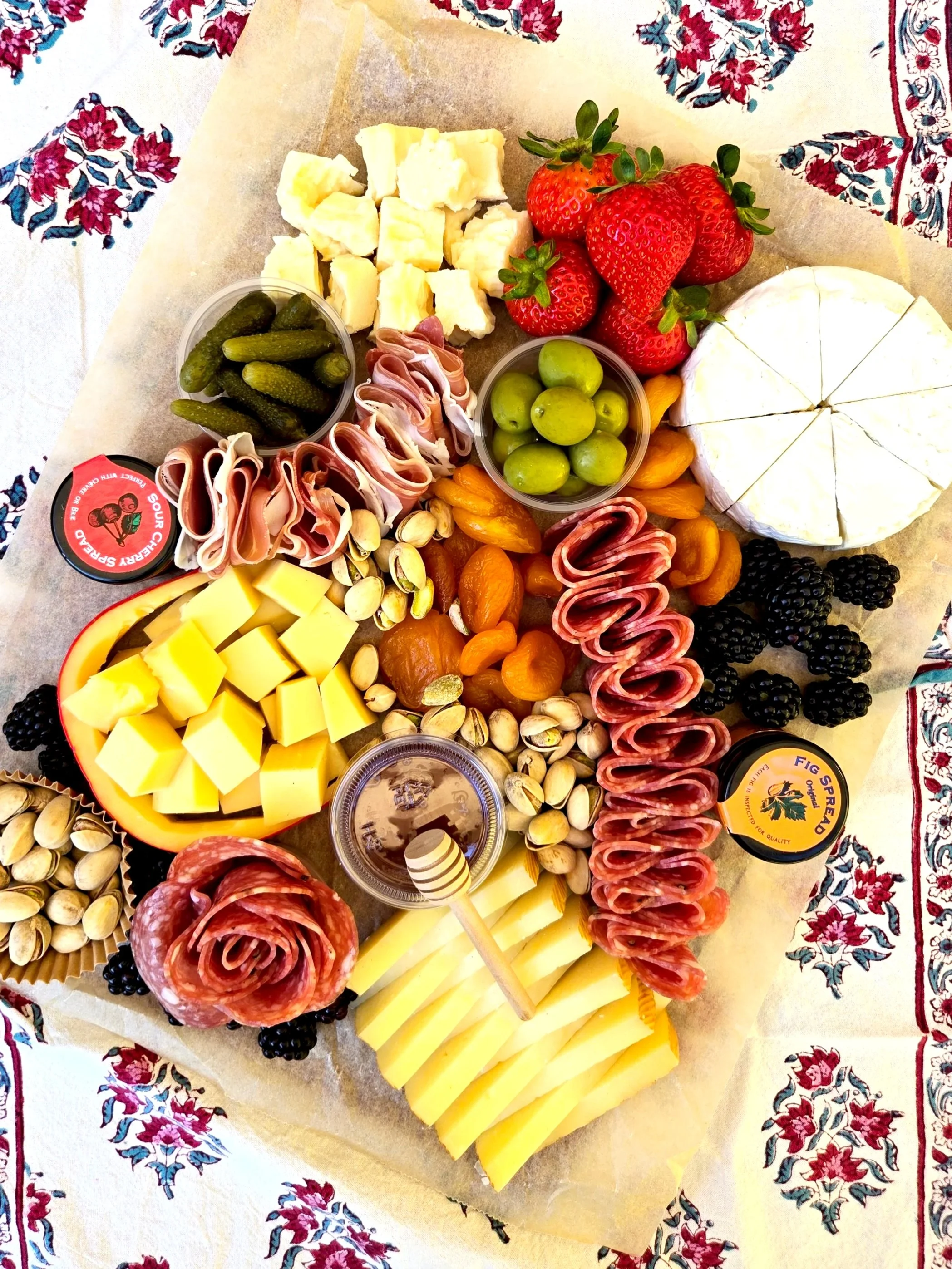 A St. Uguzo cheese platter with various cheeses, cured meats, honey, fruit, olives, pickles, nuts, dried apricots, sour cherry spread, and fig spread. Serving Ventura County, Santa Barbara County, and Northern Los Angeles County.