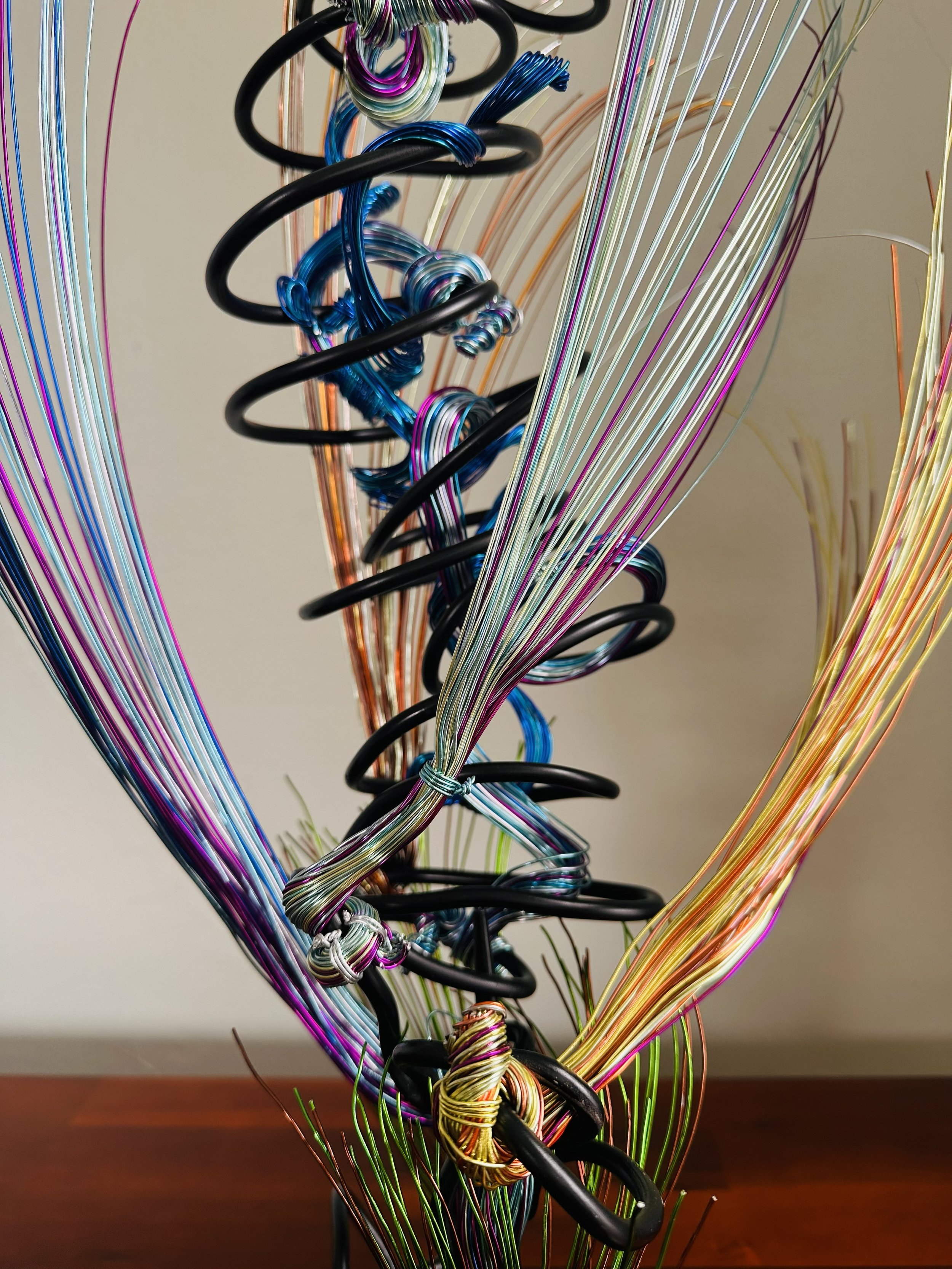 Title: "Rising"" View from front.
Dimensions:   1' 6" × 1' 6" × 2' 5"
The form stretches upward, its strands leaning into imagined air. A sculpture that feels mid‑movement — rooted below, reaching toward whatever shift is happening above.