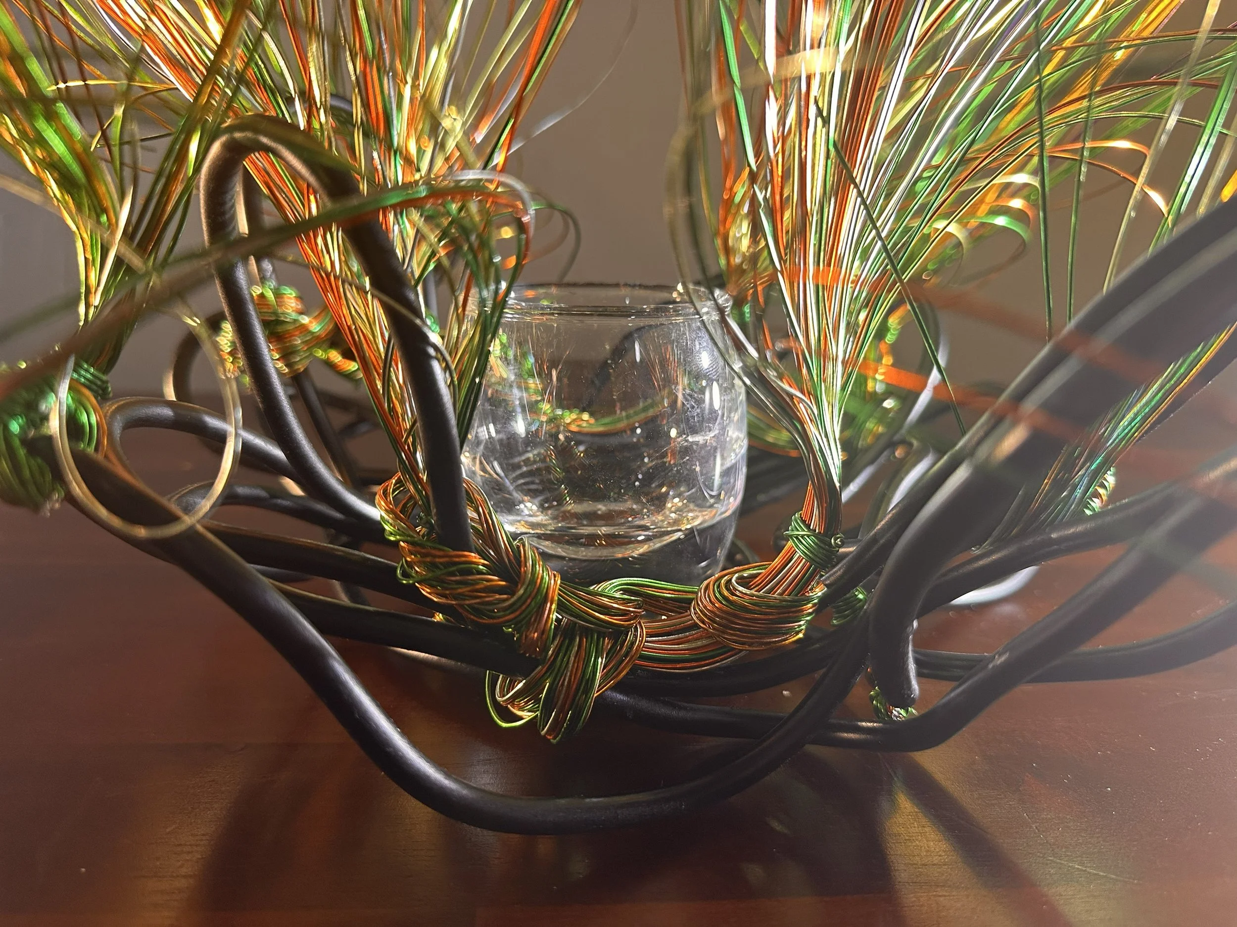 Title: "Swaying" Detail.  
Dimensions:  1' 6" × 1' 6" × 1' 6"
Wires rise in a gentle flare, as if catching the first hint of a breeze. A compact form with a quiet upward motion, holding the soft lift of something just beginning to open.



Hand‑forme