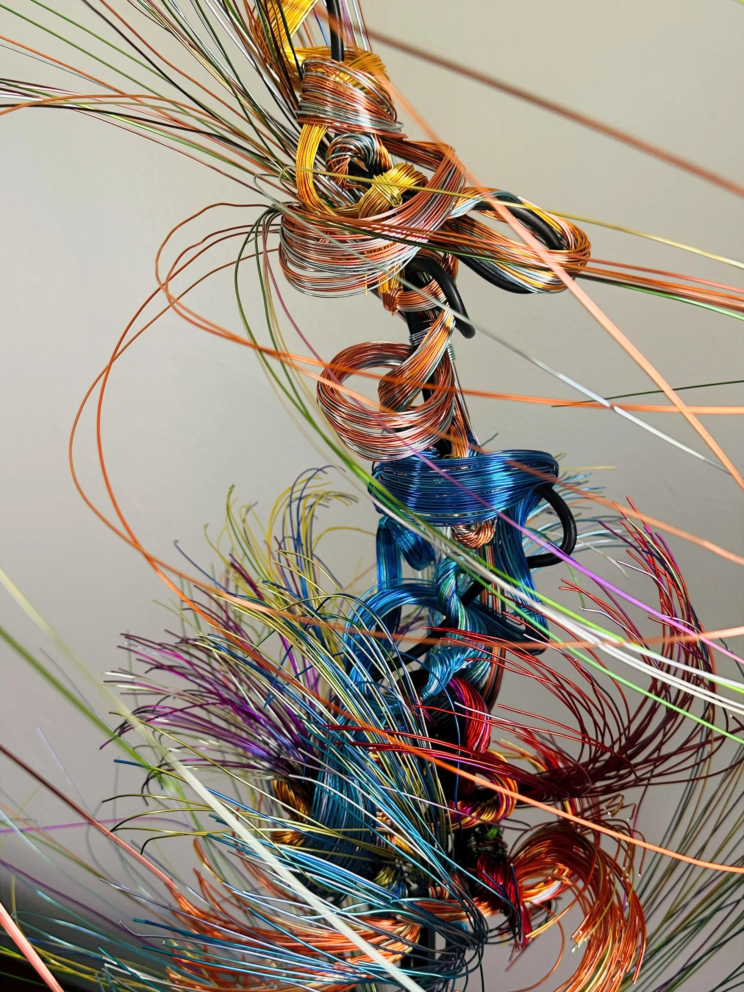 Title: Aglow in Motion with spot lighting Dimension. 2" x 2" x 4".8' 
This piece explores the soft resilience of floral forms — branches lifting, colors gathering, and thin lines swaying as if touched by light. Shaped slowly by hand, this commissione