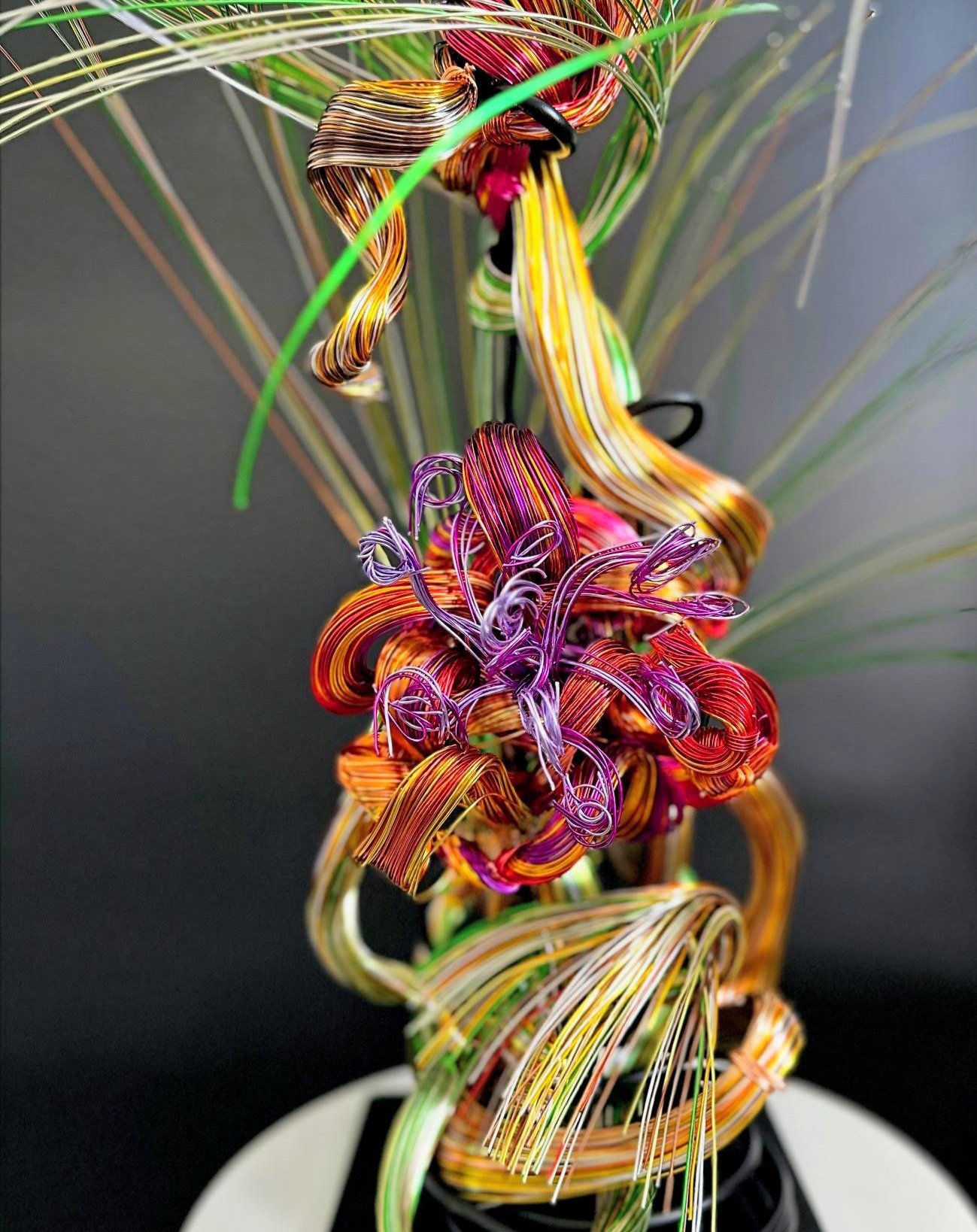 Gathering Light is a wire sculpture shaped as a single, blooming form. Blending copper, green, and violet tones, it explores emergence, focus, and upward motion. Inspired by nature and created in Petaluma, this piece reflects the quiet strength of tr