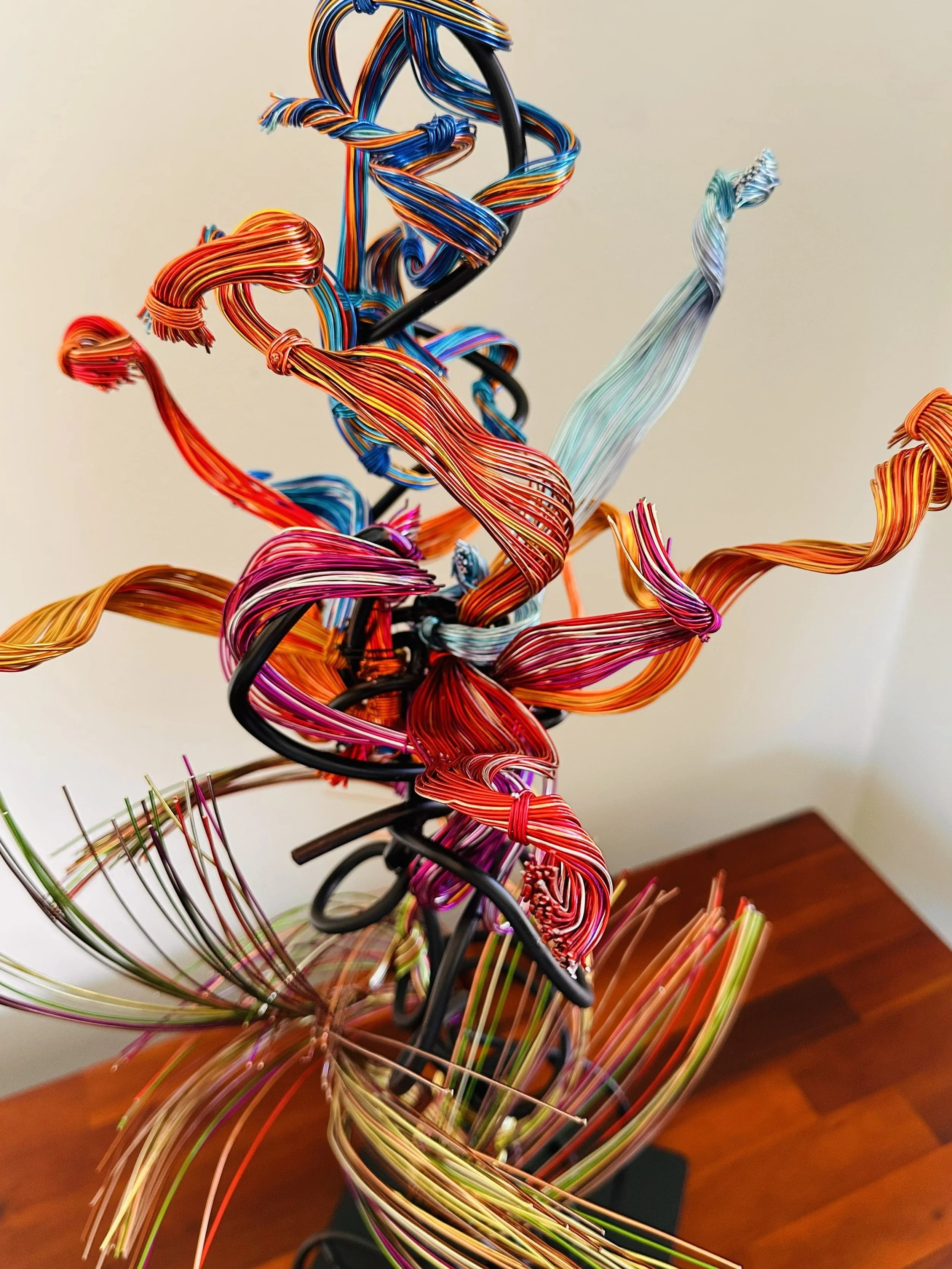 "Paradise" Detail view of the pedals. Day lighting   
Description:   Interwoven metallic lines creating a dynamic, ribbon‑like movement — a piece alive with color, tension, and flow.

