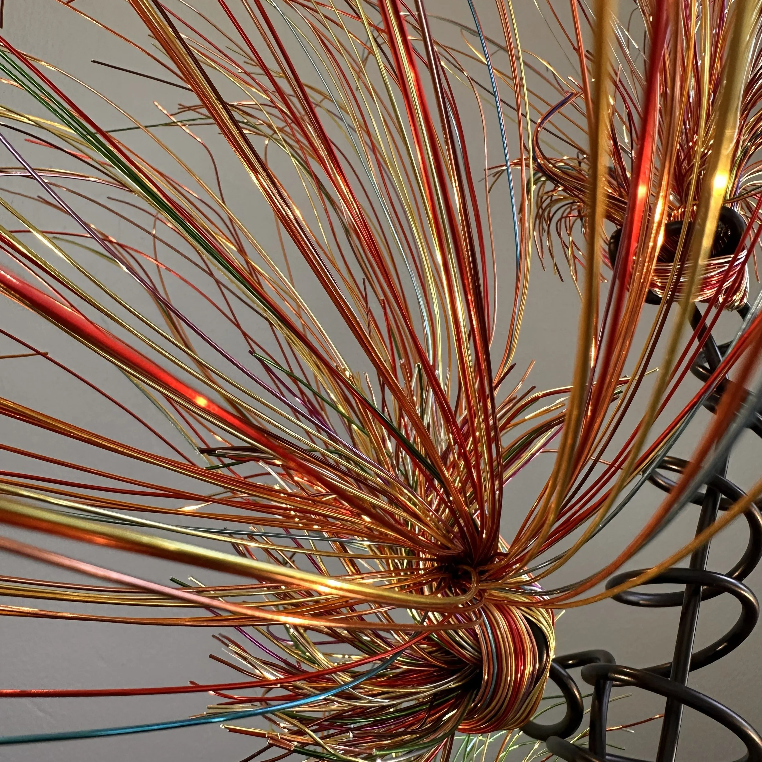 Title:  "Luminous" 
Dimensions:  2' × 2 '× 2' 8”
Description: Fine wires flare outward like petals deciding to open, catching the light in shifting tones of copper, ember, and moss. The piece holds the stillness of a plant just on the edge of becomin