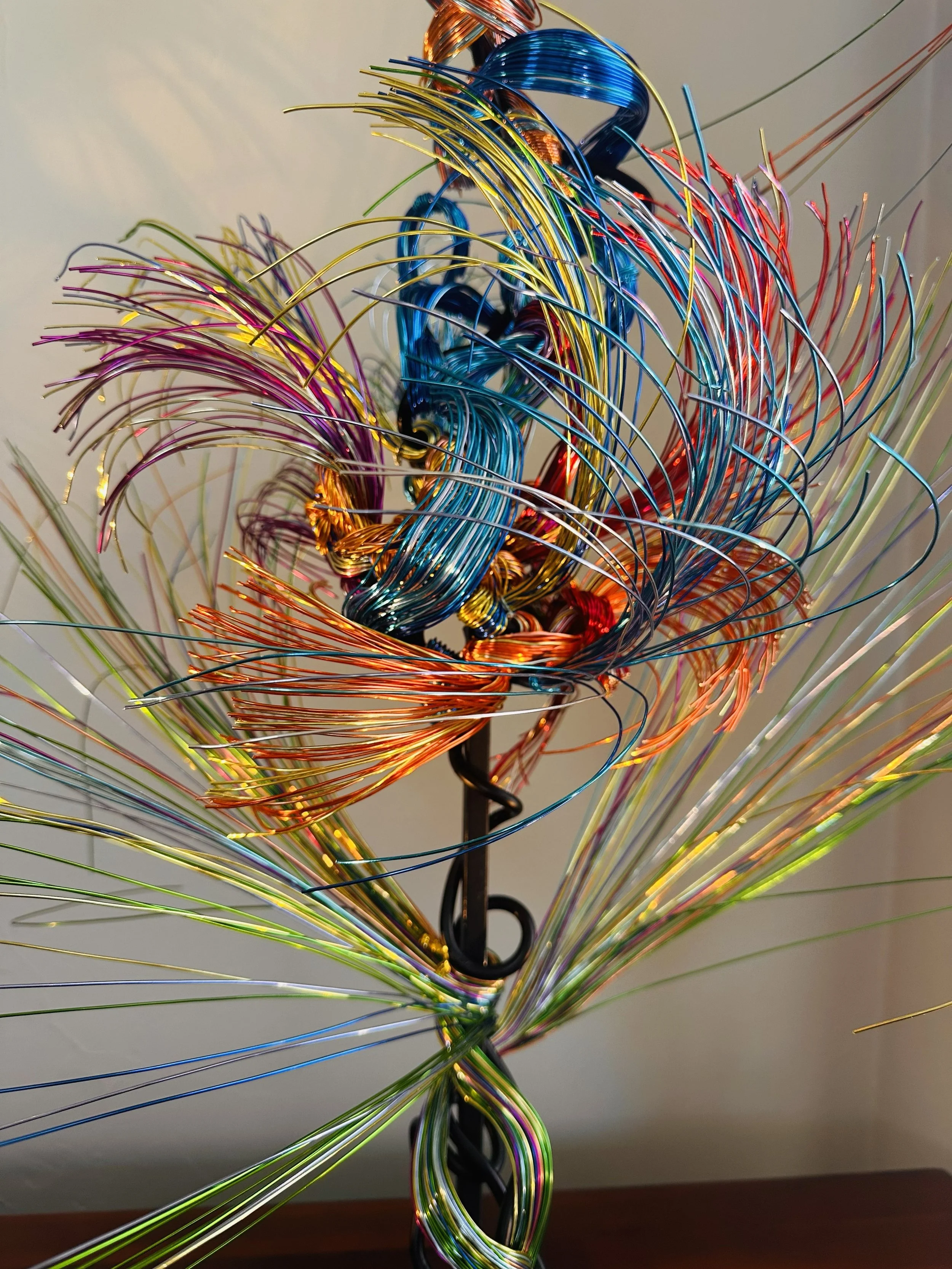 Title: Aglow in Motion with spot lighting Dimension. 2" x 2" x 4".8' 
This piece explores the soft resilience of floral forms — branches lifting, colors gathering, and thin lines swaying as if touched by light. Shaped slowly by hand, this commissione