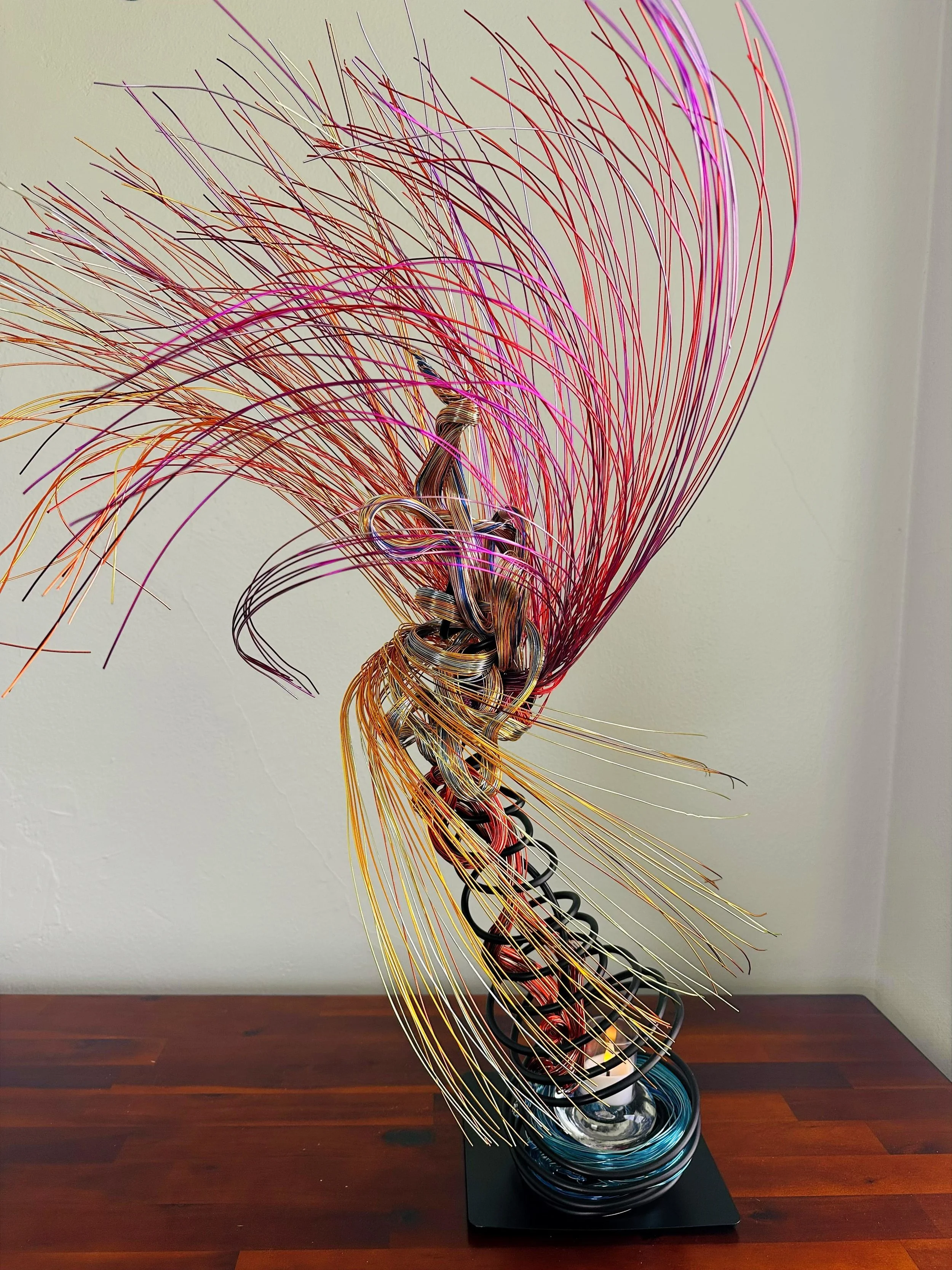 Title:  "Swaying" 
Dimensions: 2” x 2” 10”× 2” 10’
Description: Swaying reflects palms caught in a shifting breeze, with upper and lower branches moving in opposite directions. A quiet balance forms around the open space for the votive, where earth‑w
