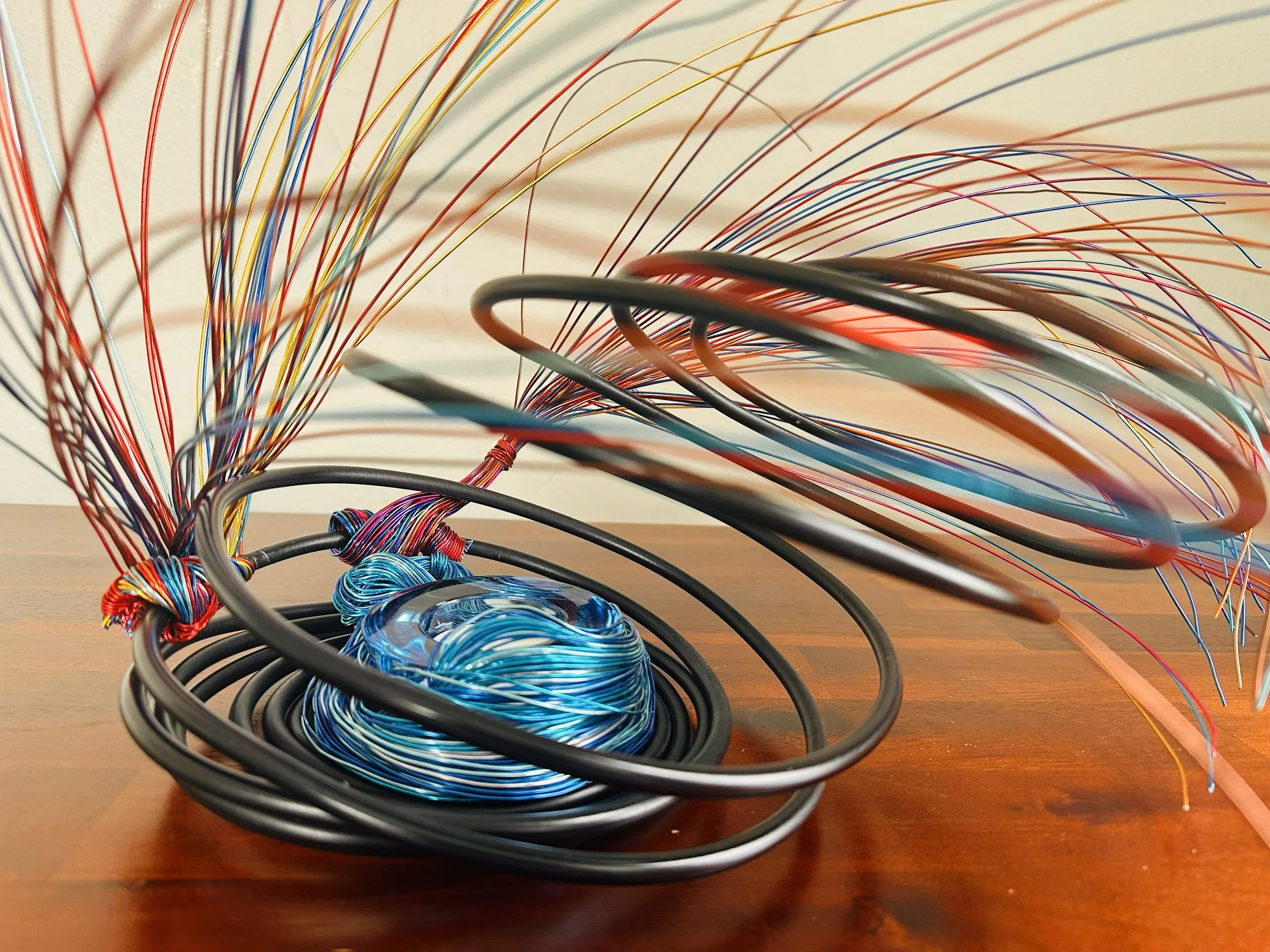 A star-shaped sculpture made of colorful wires on a wooden table.