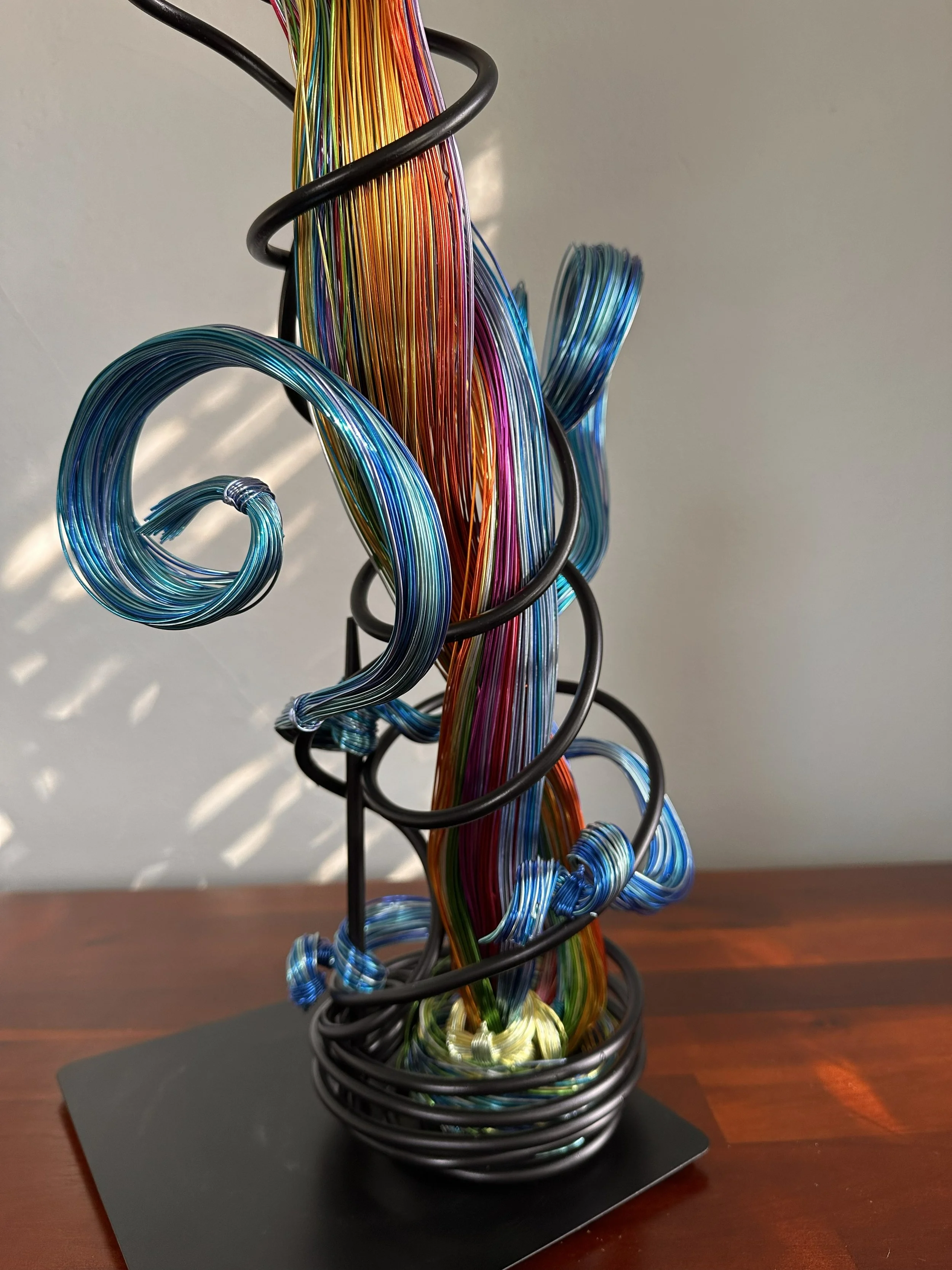 Title: "Flowing" 
Dimensions:  1' 8" × 1' 8" × 3' 0"
A red flare rises through volcanic heat, branching into color before opening into a glowing, palm‑like burst.