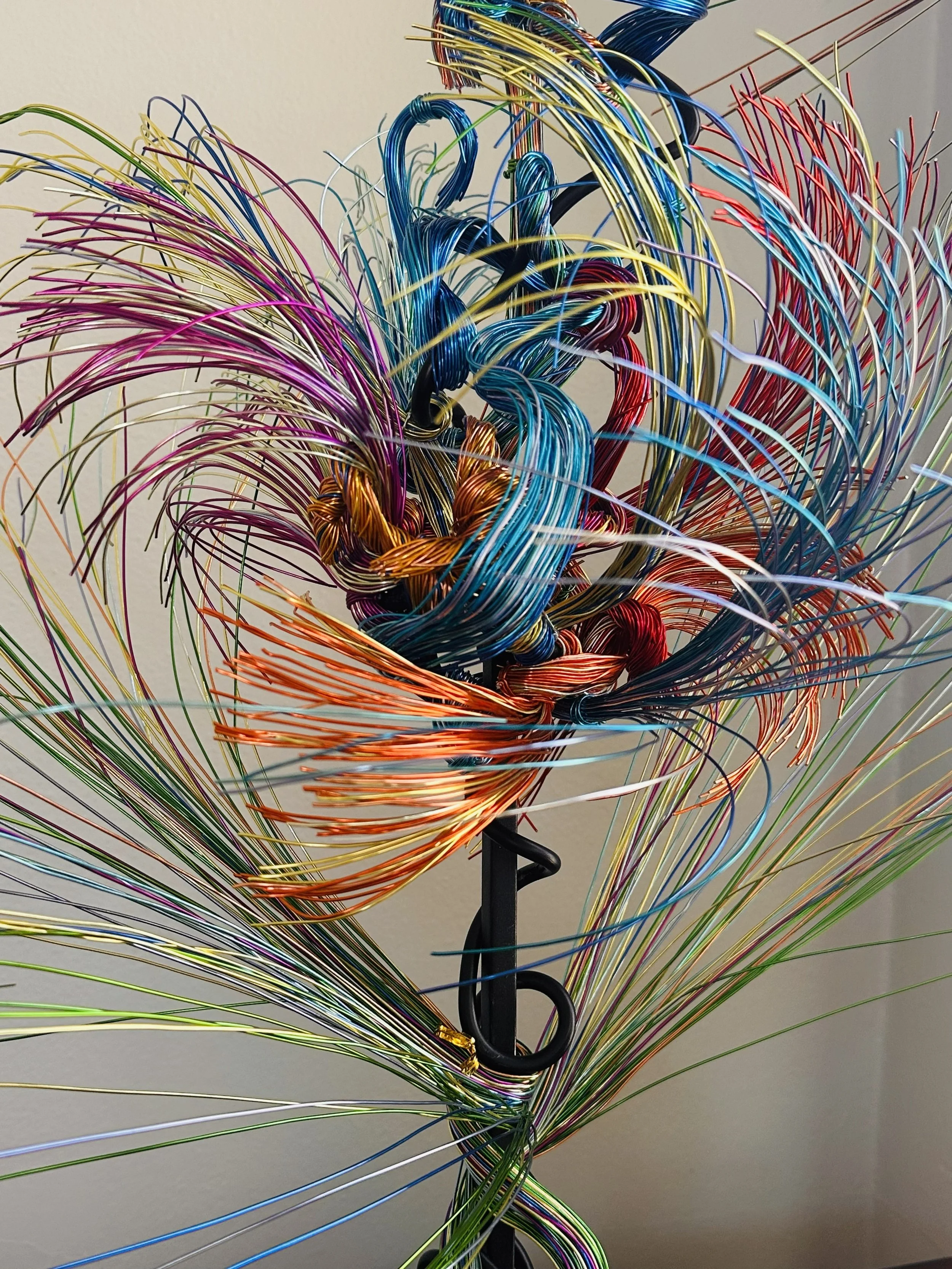 Title: Aglow in Motion. Center detail view 
Dimension. 2" x 2" x 4".8' 
This piece explores the soft resilience of floral forms — branches lifting, colors gathering, and thin lines swaying as if touched by light. Shaped slowly by hand, this commissio