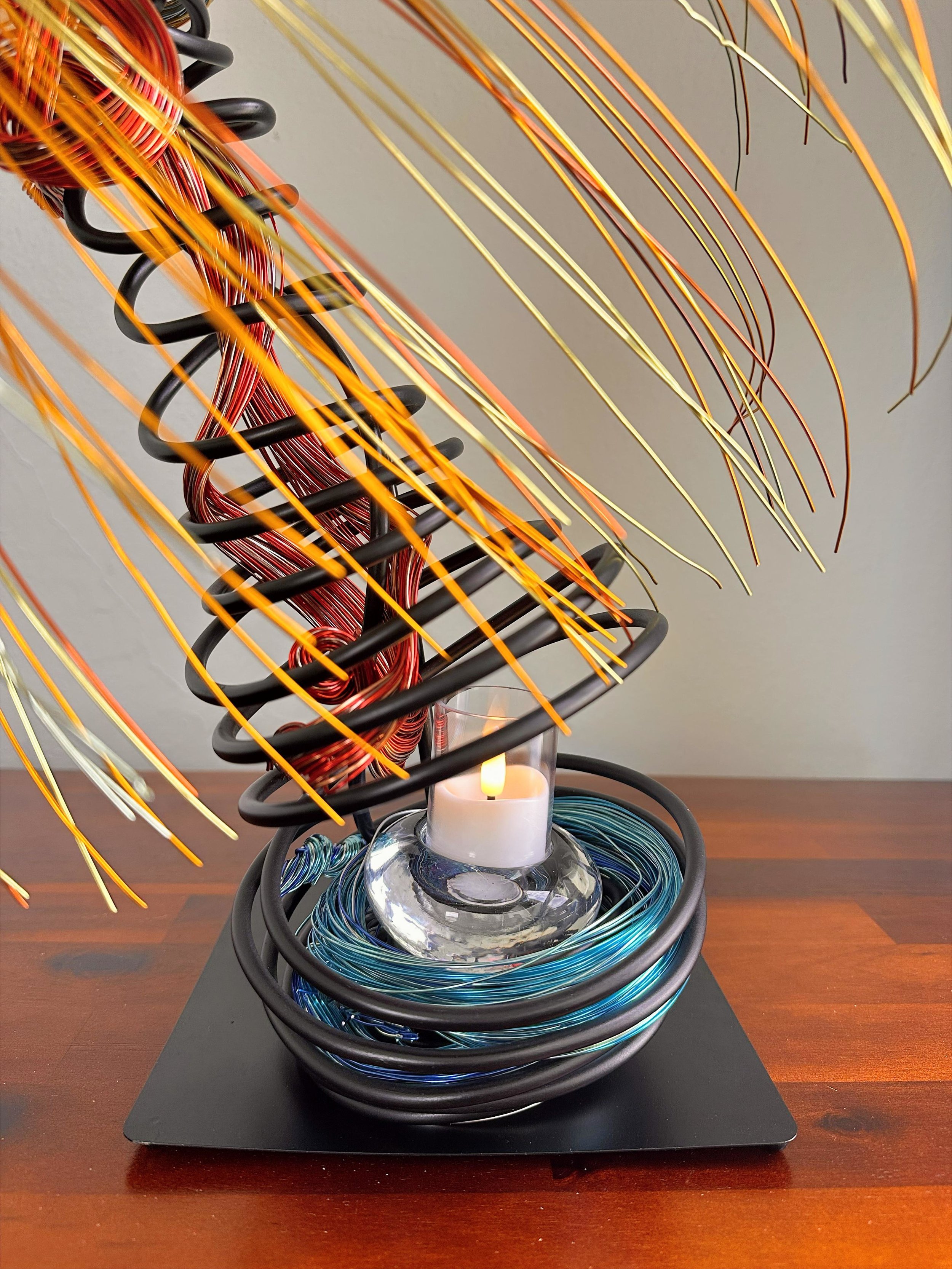 Title:  "Swaying" 
Dimensions: 2” x 2” 10”× 2” 10’
Description: Swaying reflects palms caught in a shifting breeze, with upper and lower branches moving in opposite directions. A quiet balance forms around the open space for the votive, where earth‑w