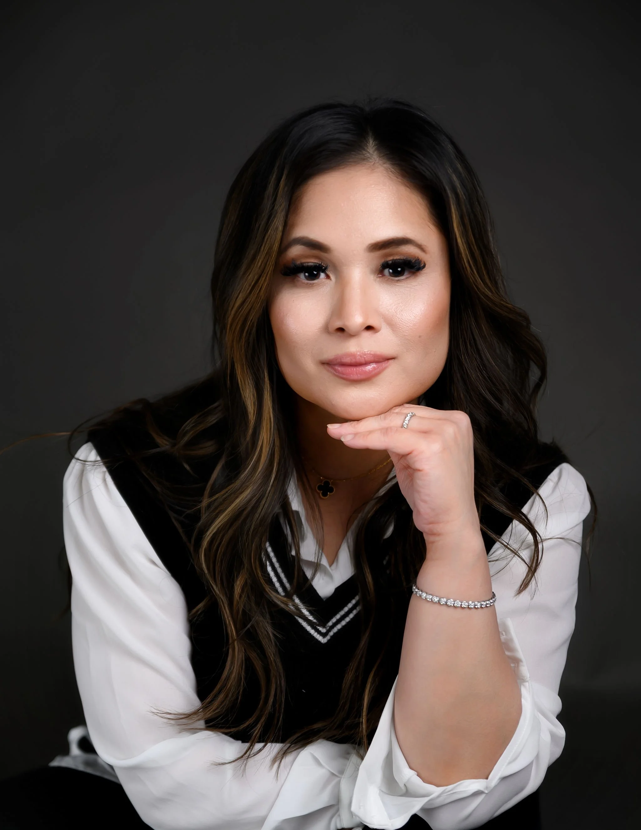 A woman with long dark hair and light skin, wearing a white blouse and black vest, Beauty Period Aesthetics in Wasco, IL offers Botox, dermal fillers, microneedling, wellness injections, and weight loss treatments for natural results.