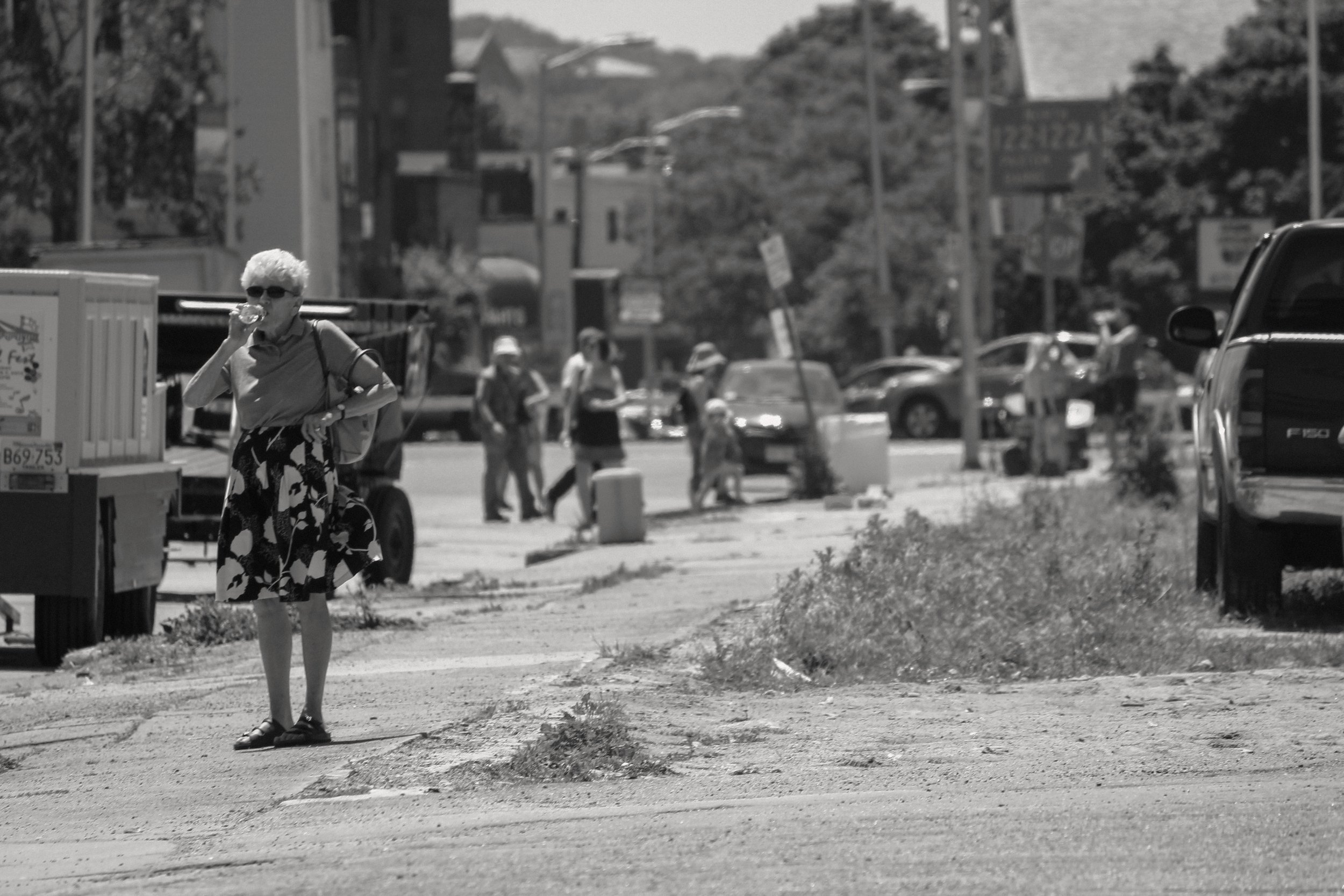 Woman takes a sip of water on sidewalk