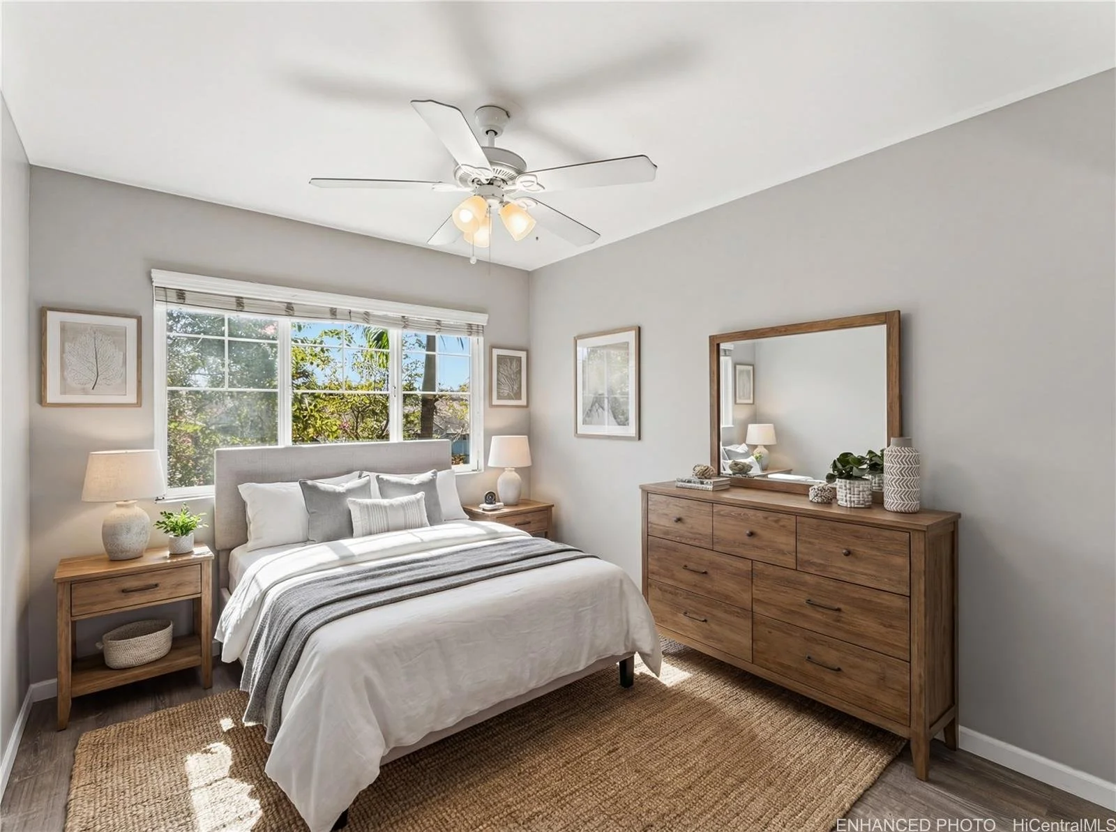 A bedroom with a bed, nightstands, and a dresser with a mirror, decorated with natural colors and textures, with a window showing trees outside.