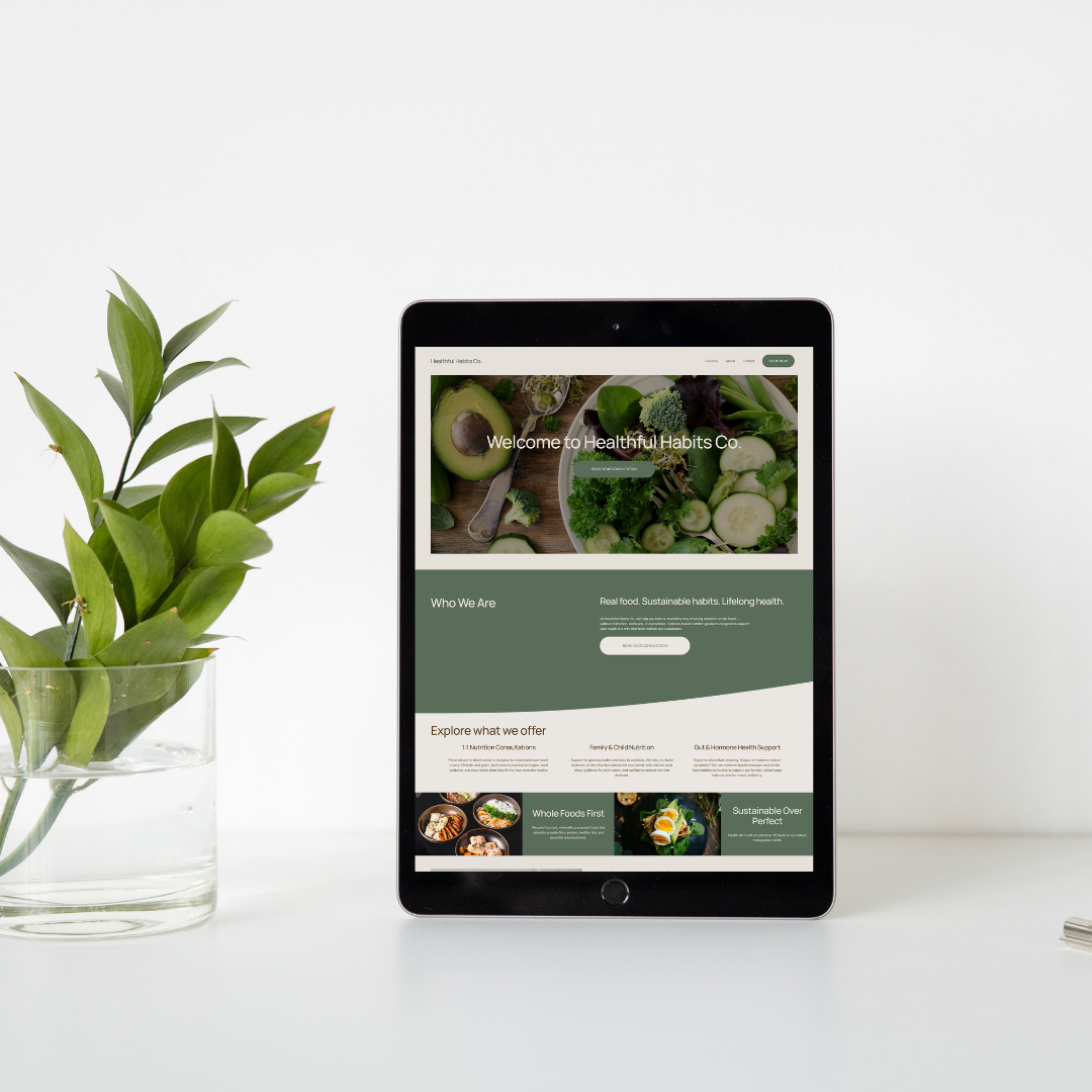 Tablet displaying the homepage of Healthy Habits Co. website with images of fresh vegetables and green salad, next to a glass planter with green leafy plant.