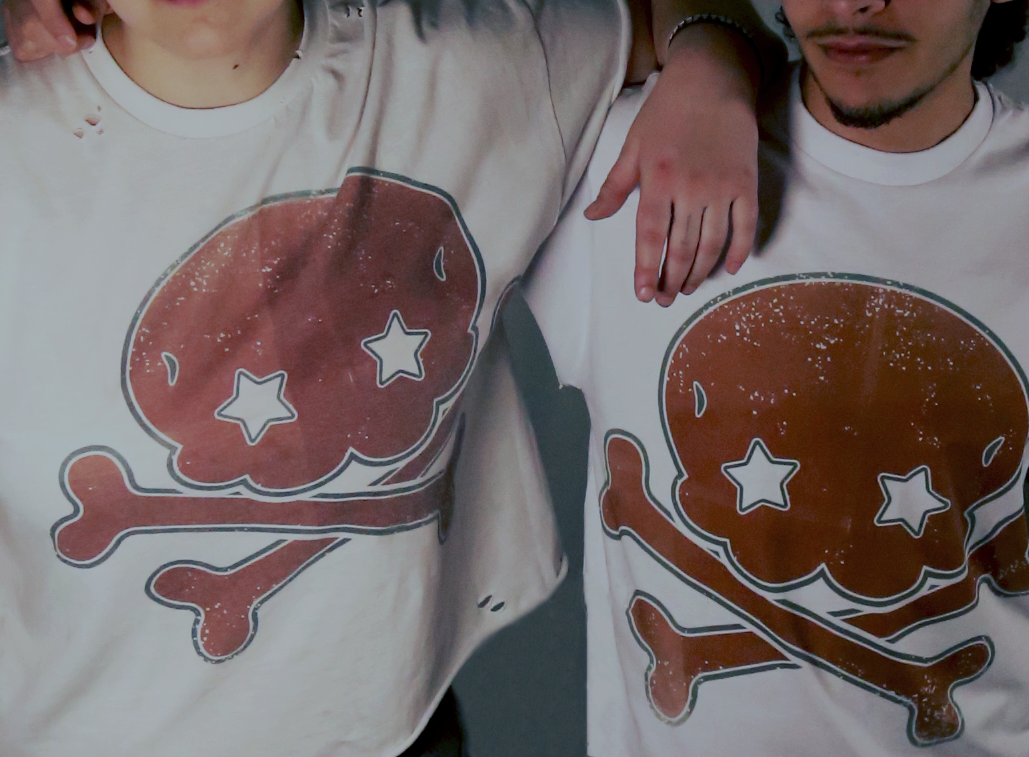 Two people are wearing white T-shirts with a graphic of a cooked chicken leg with star-shaped eyes and a crossbones design.