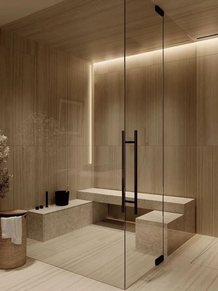 Modern steam room with wooden walls, a stone bench, glass door with black handles, and subtle built-in lighting.