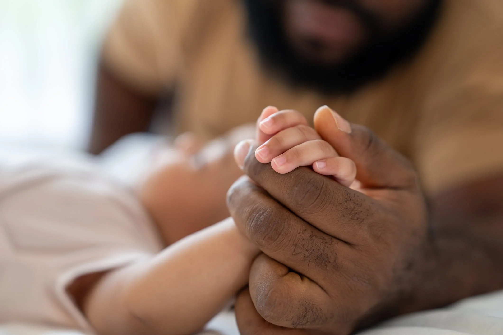 Father gently holding his newborn baby’s hand, symbolizing love, support, and neonatal care.
