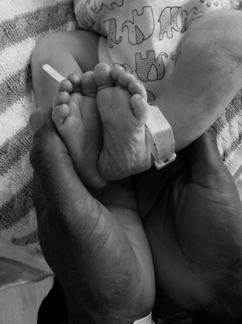 Newborn baby’s feet resting in a parent’s hands, symbolizing protection, neonatal care, and family support.
