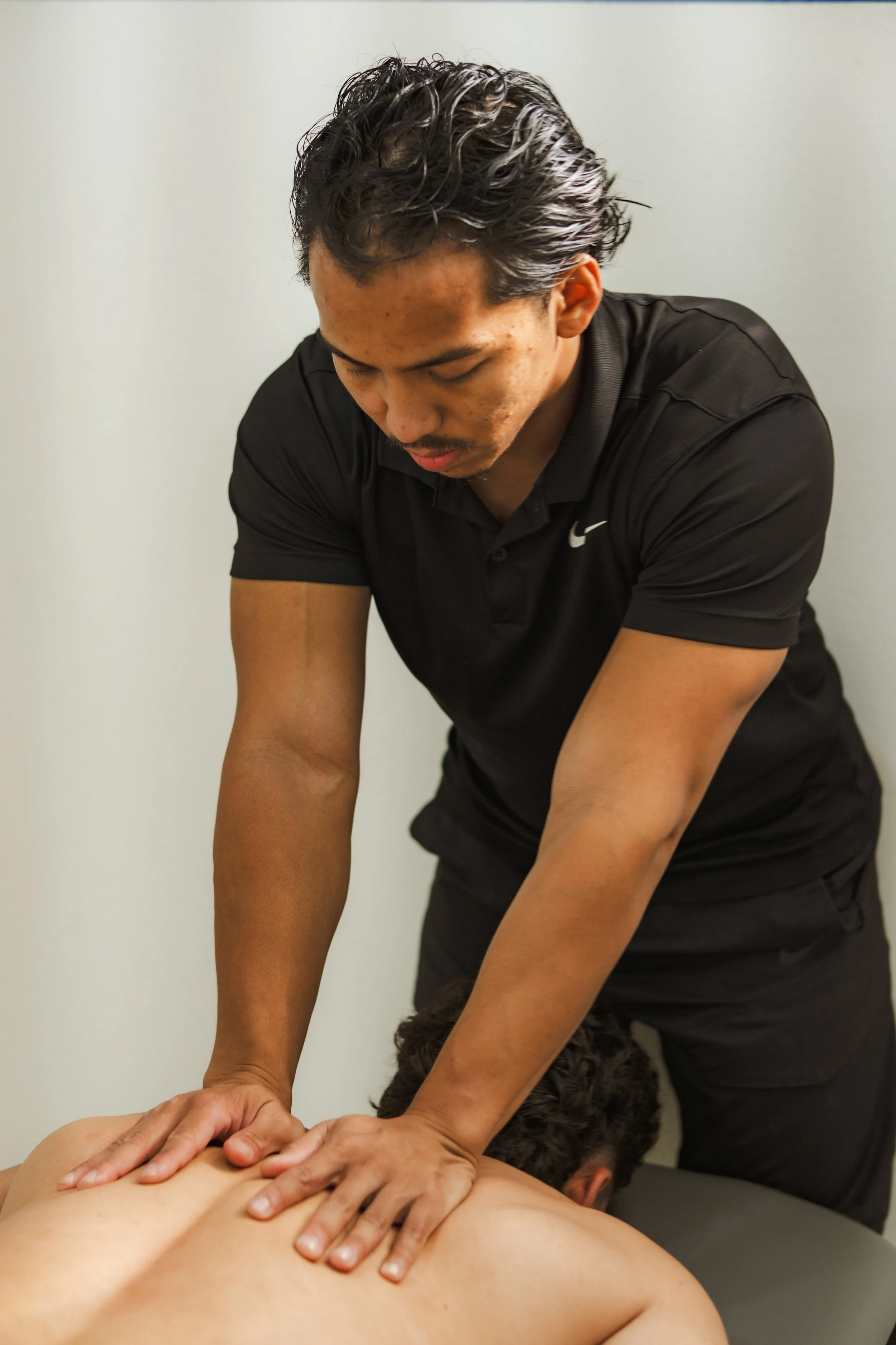 Man receiving a back massage from a professional massage therapist in a clinical setting.