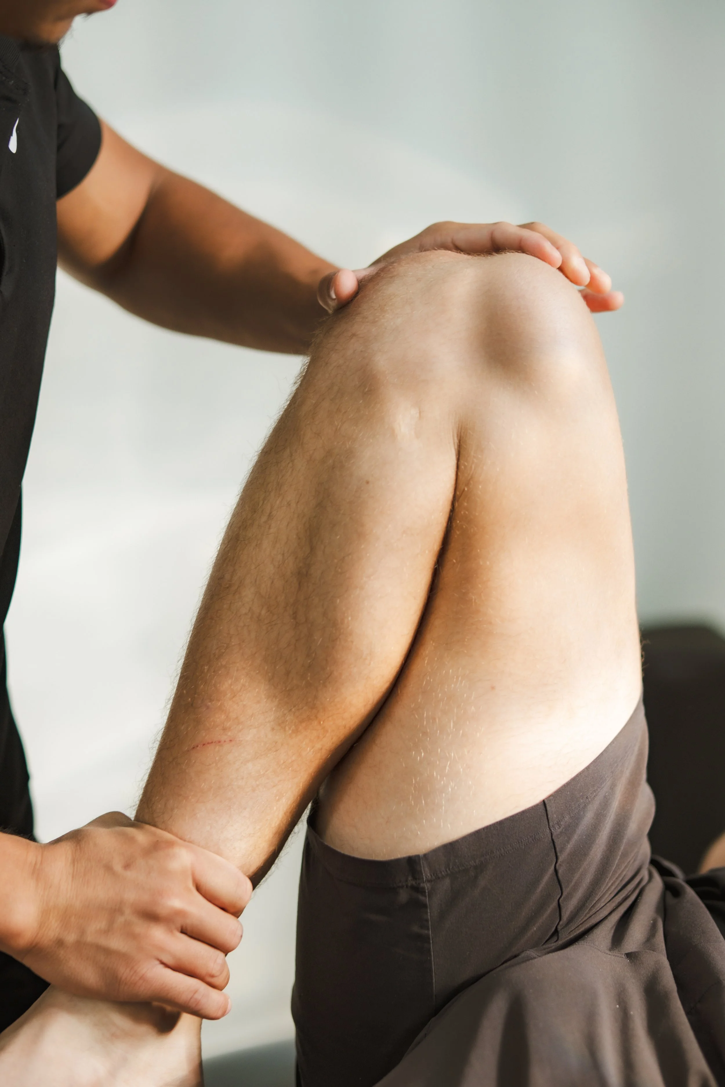 A person giving a hand massage to someone who is seated, with focus on the person's back and shoulder.