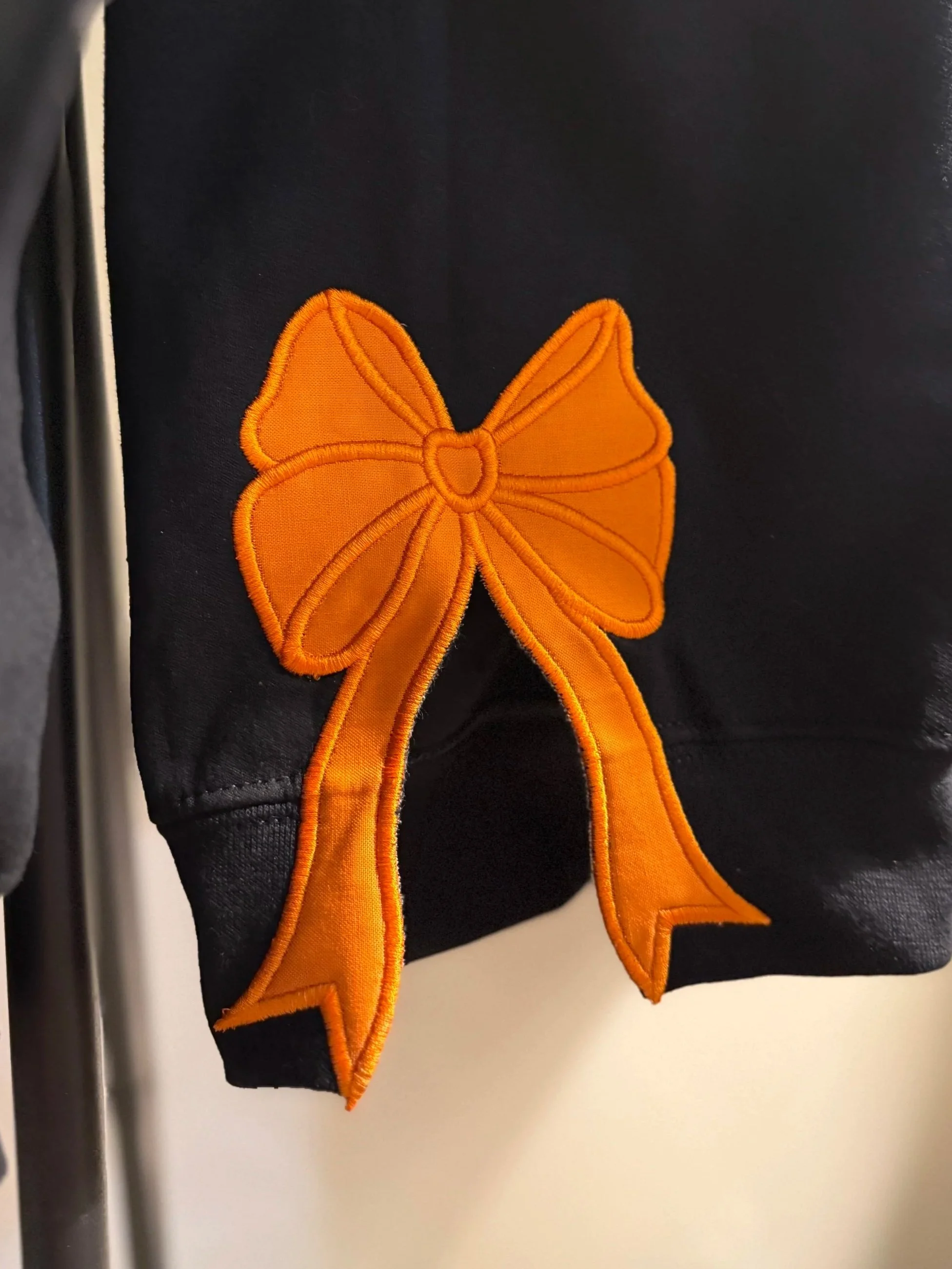 Black garment with orange butterfly-shaped embroidered patch.