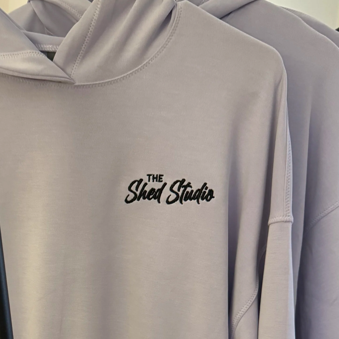 A white hoodie with the text "The Shred Studio" embroidered in black on the front.