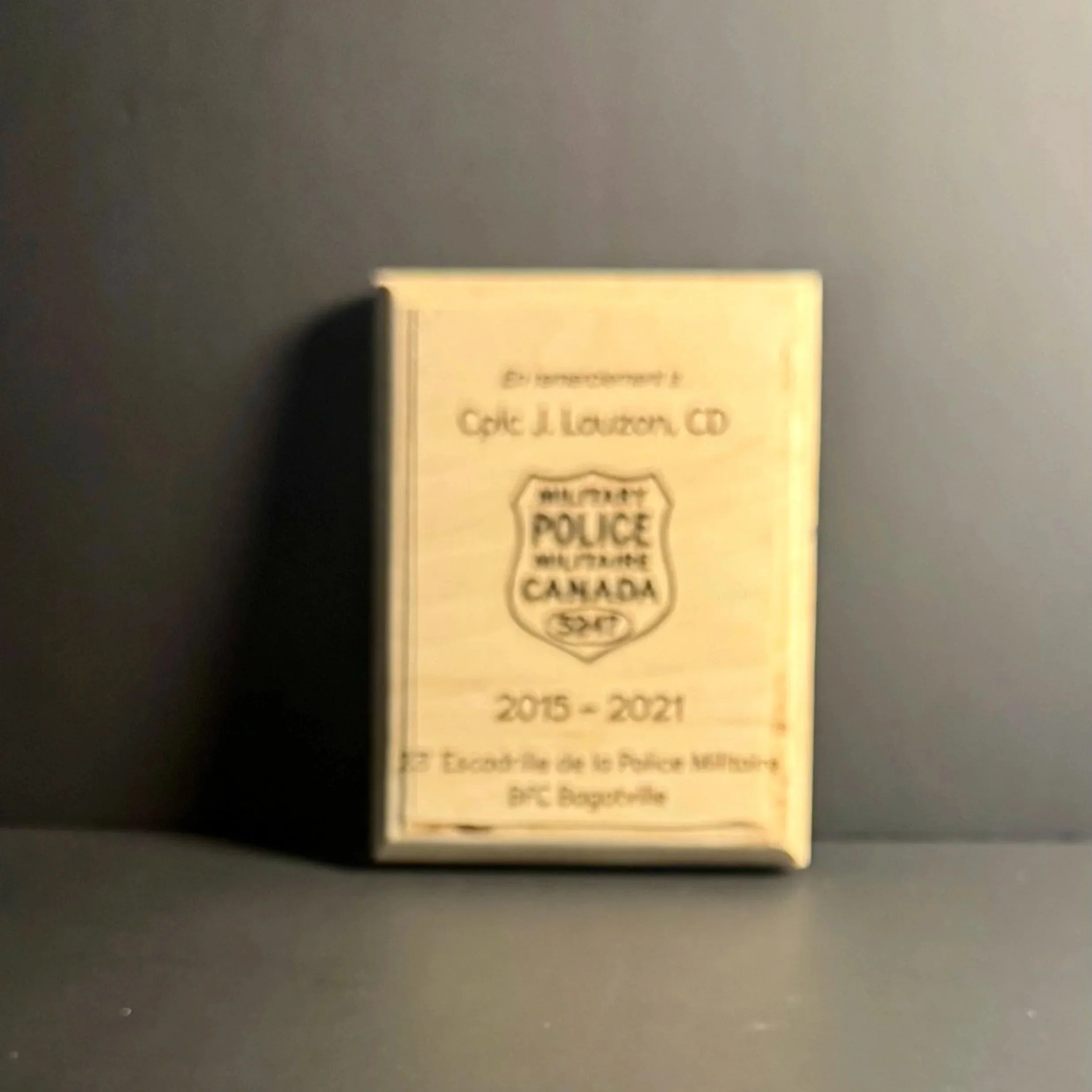 Une plaque commémorative avec un logo de la police militaire canadienne sur une surface sombre.