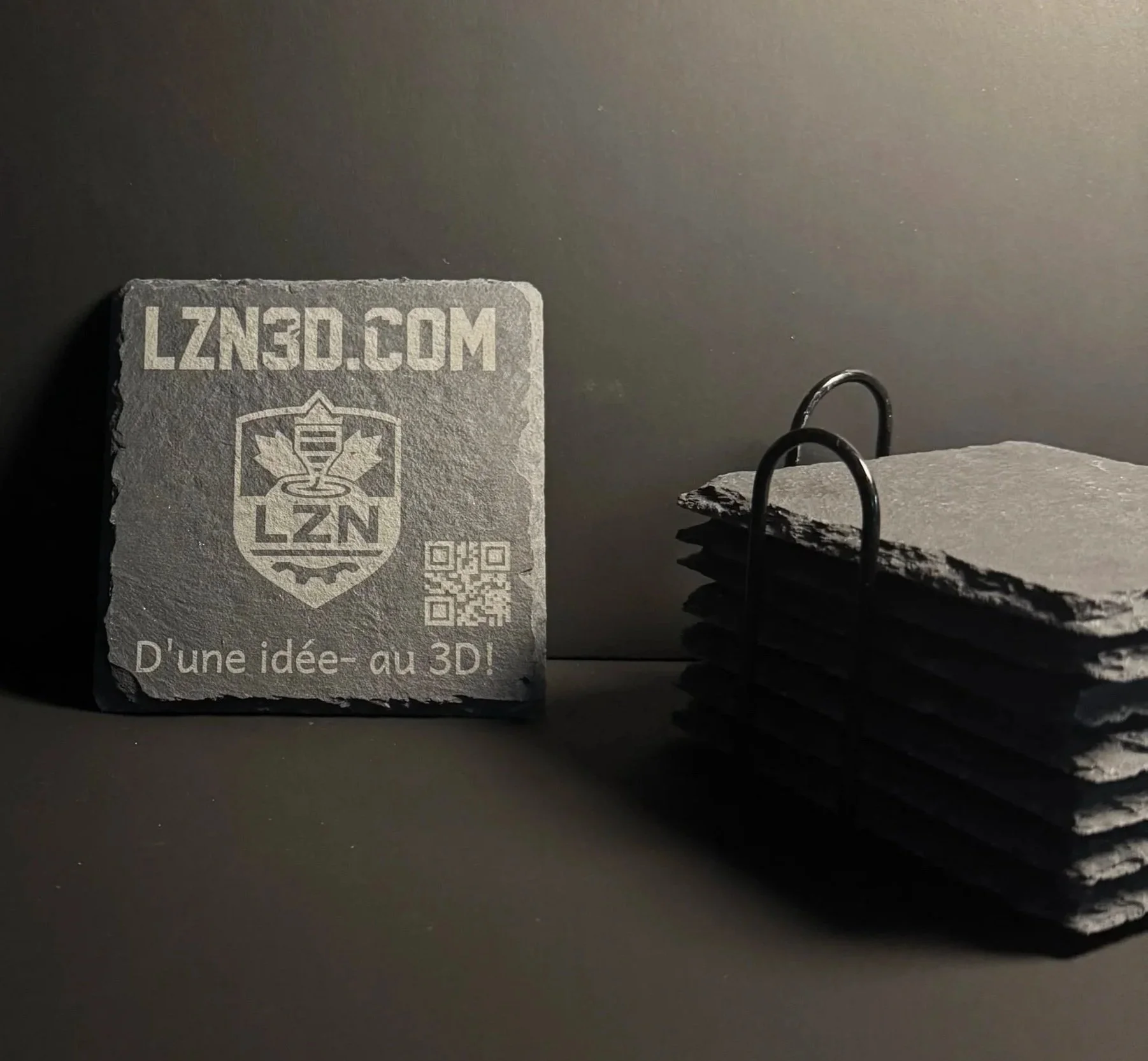 Un sous-verre en pierre avec le texte 'LZN30.COM' et un symbole de logo, avec un support en métal pour l'ensemble de sous-verre.