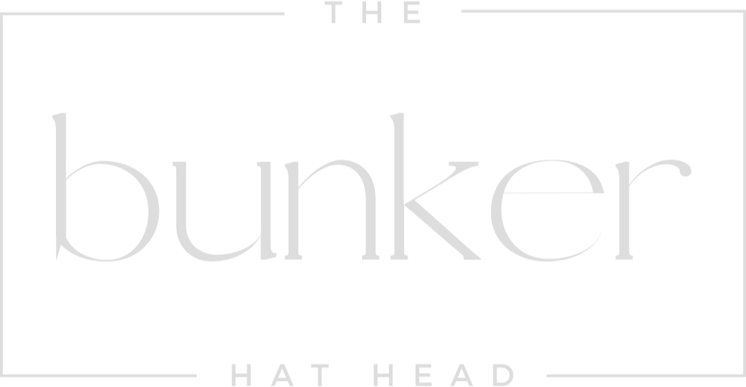 Logo with the words 'The Bunker Hat Head' in gray text on a black background.