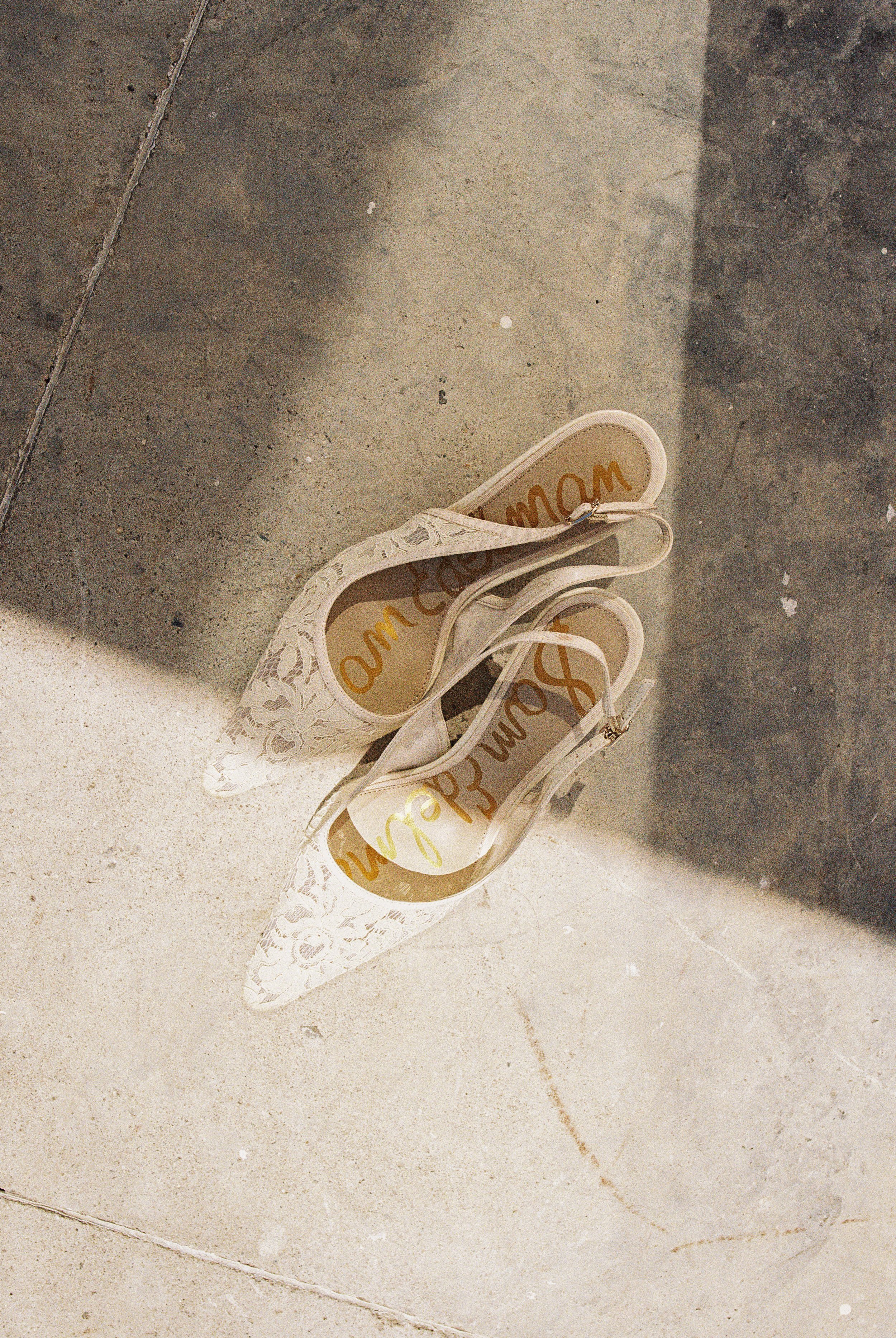 Lace bridal heels with custom gold script, wedding detail photography capturing refined and personal touches.
