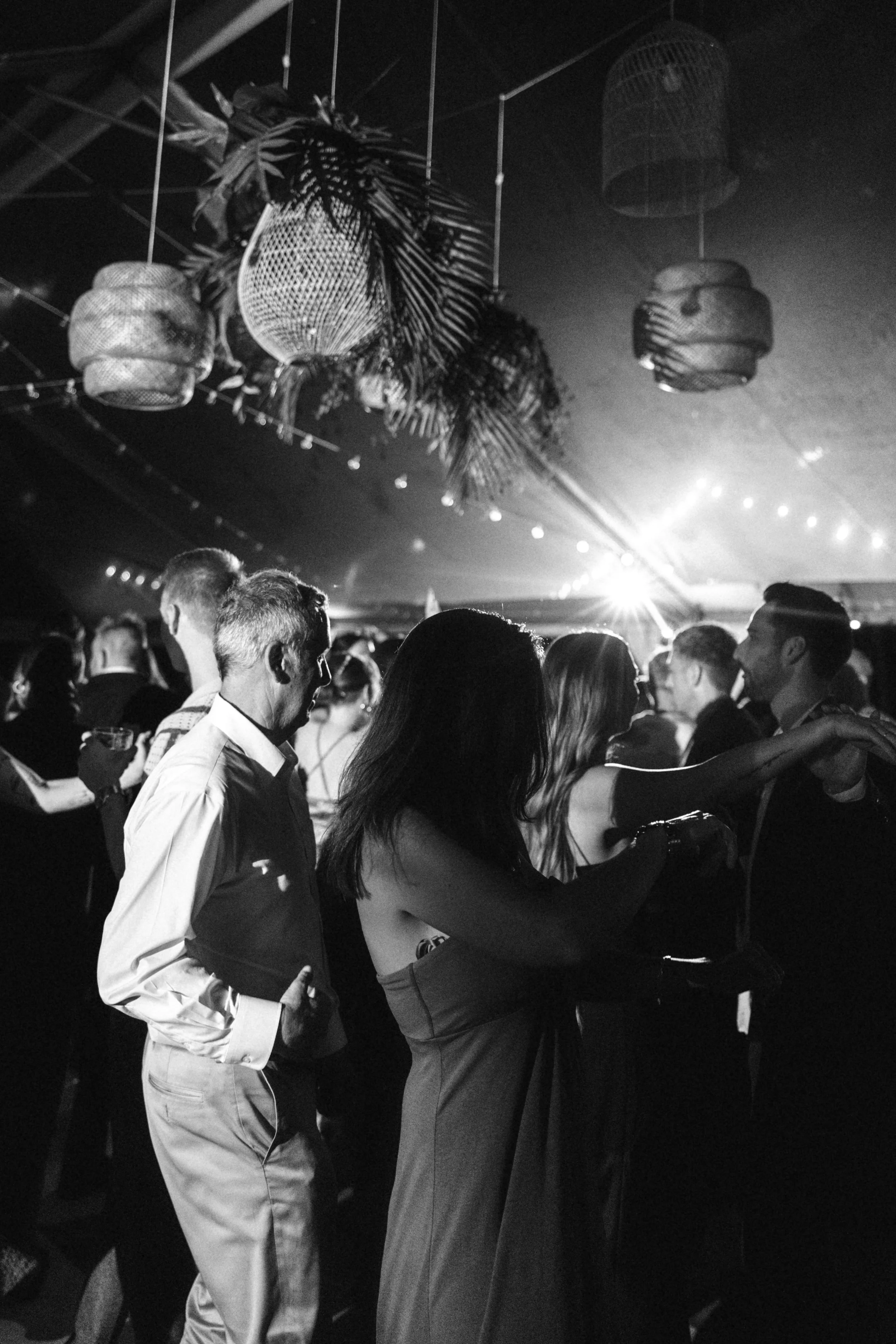 Candid wedding reception dance floor under paper lanterns, editorial flash photography capturing a lively celebration.