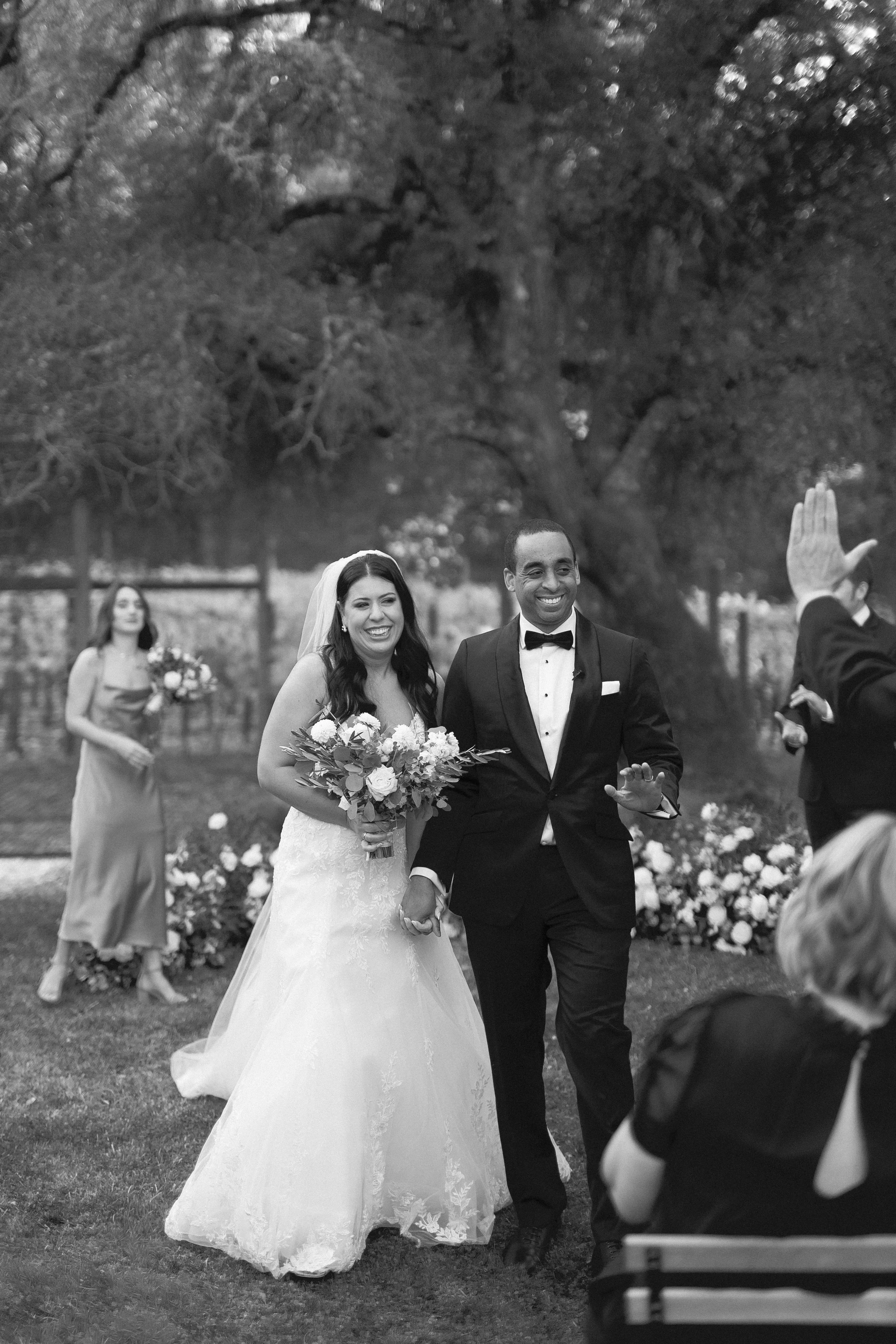 Black and white 35mm film wedding moment, candid newlywed exit surrounded by guests and emotion.