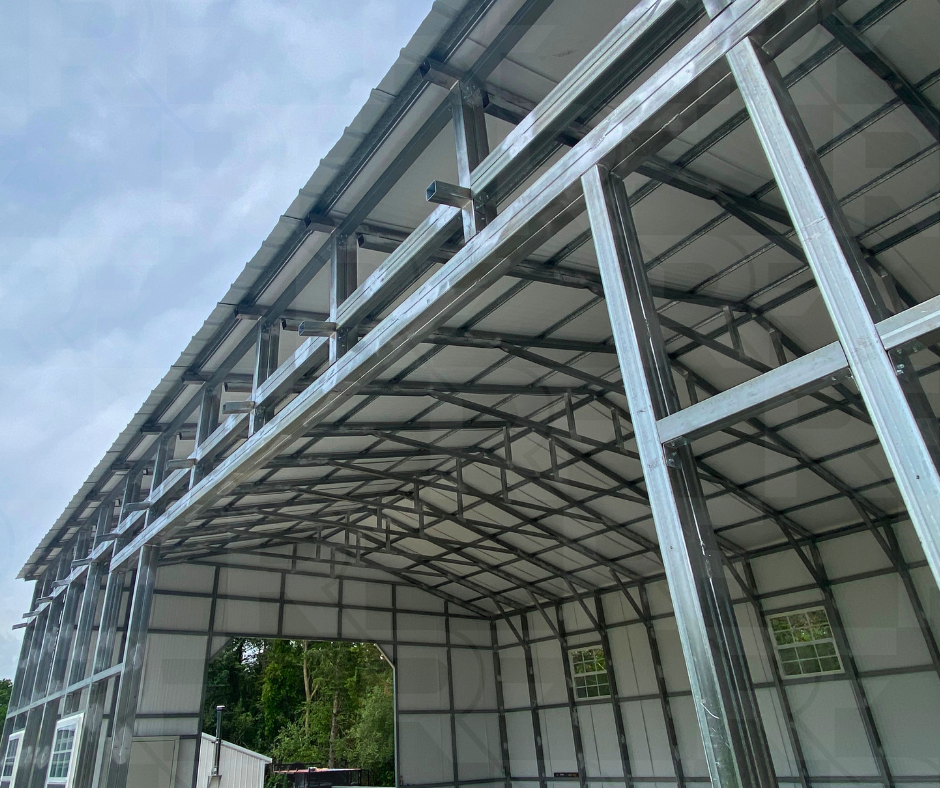 Steel frame structure of a new building under construction, open front with trees and sky in the background.