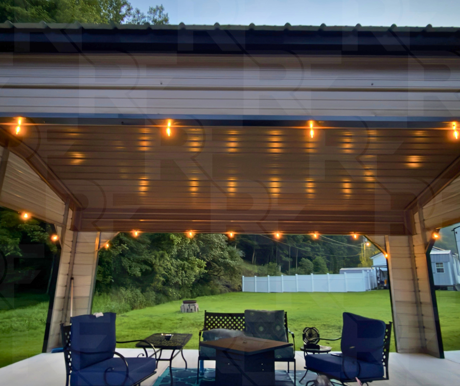 Covered outdoor patio with string lights, blue chairs, a small table, and a lush green backyard with a white fence.
