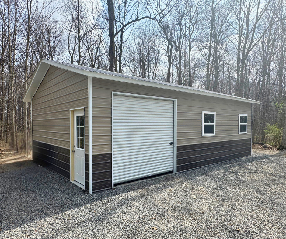 A metal garage building with beige and dark brown siding, a large roll-up door, a side door with a window, and two small windows, situated on gravel with trees in the background.