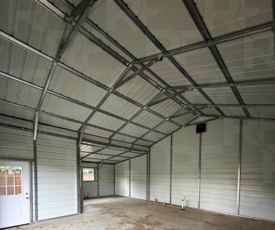Empty interior of a metal garage with a curved roof, concrete floor, small window, and a door with a window panel.