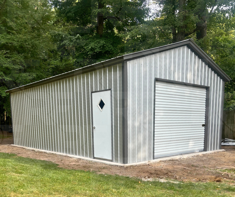 A  gray and black vertical sided metal storage shed with a roll-up door and a side door with a diamond window, situated on a grassy area with trees in the background.
