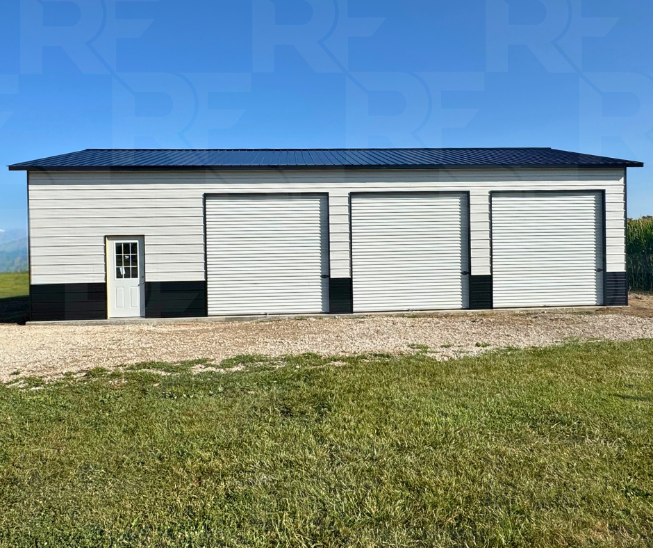 White metal garage with black roof and three roll-up garage doors
