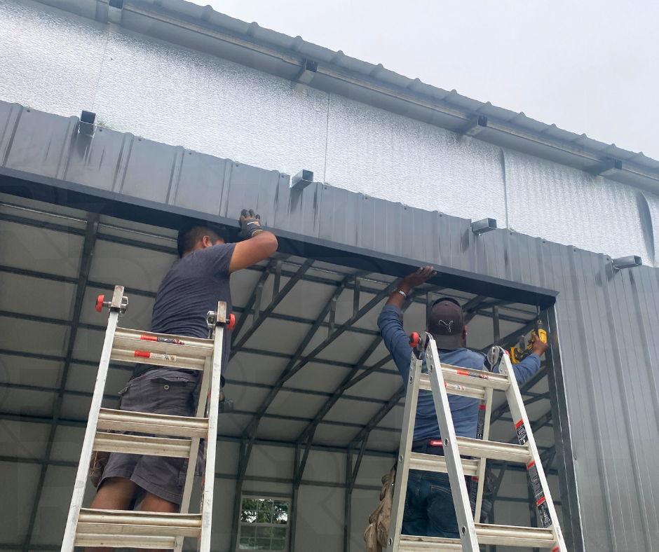 Two workers on ladders installing or repairing a metal structure on a building.