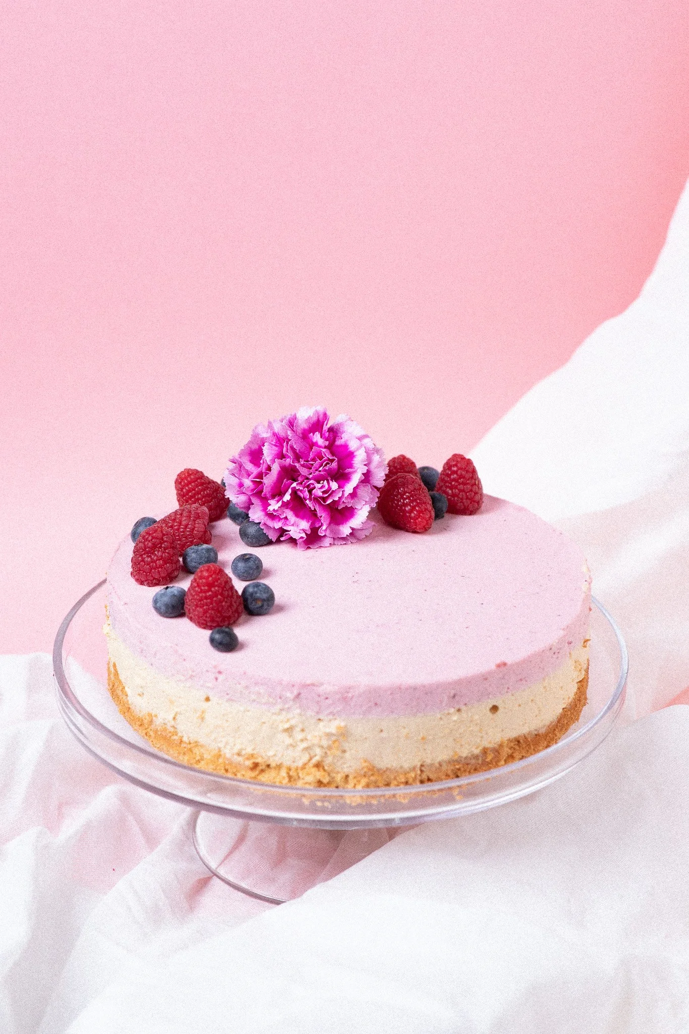 Minimalistinen kakku marjoilla pinkkiä taustaa vasten – moderni tuotekuvaus ruokabrändin visuaaliseen ilmeeseen