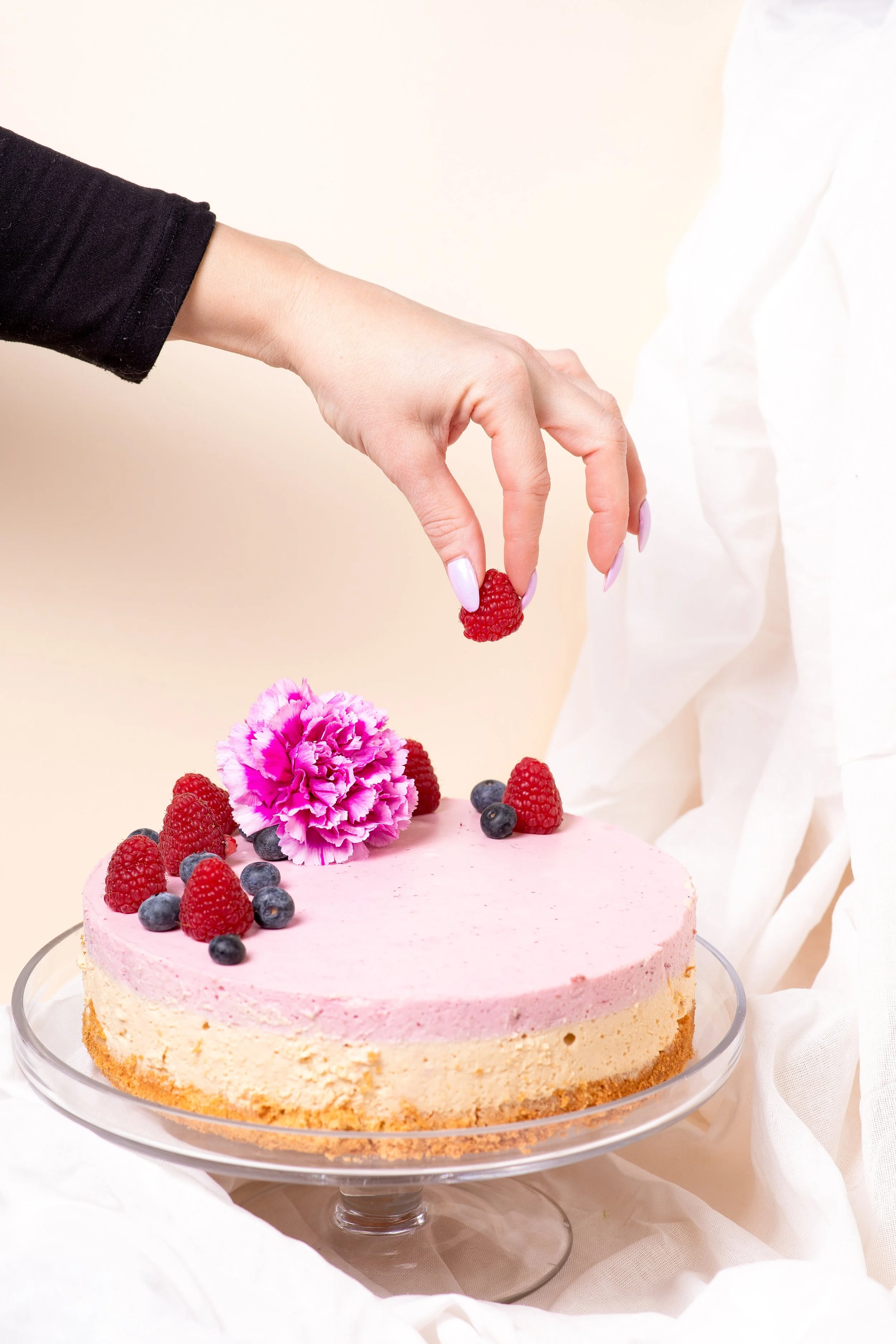 Brändikakku viimeistellään marjoilla – visuaalinen tuotekuvaus ruokabrändille pehmeässä ja vaaleassa sävymaailmassa.