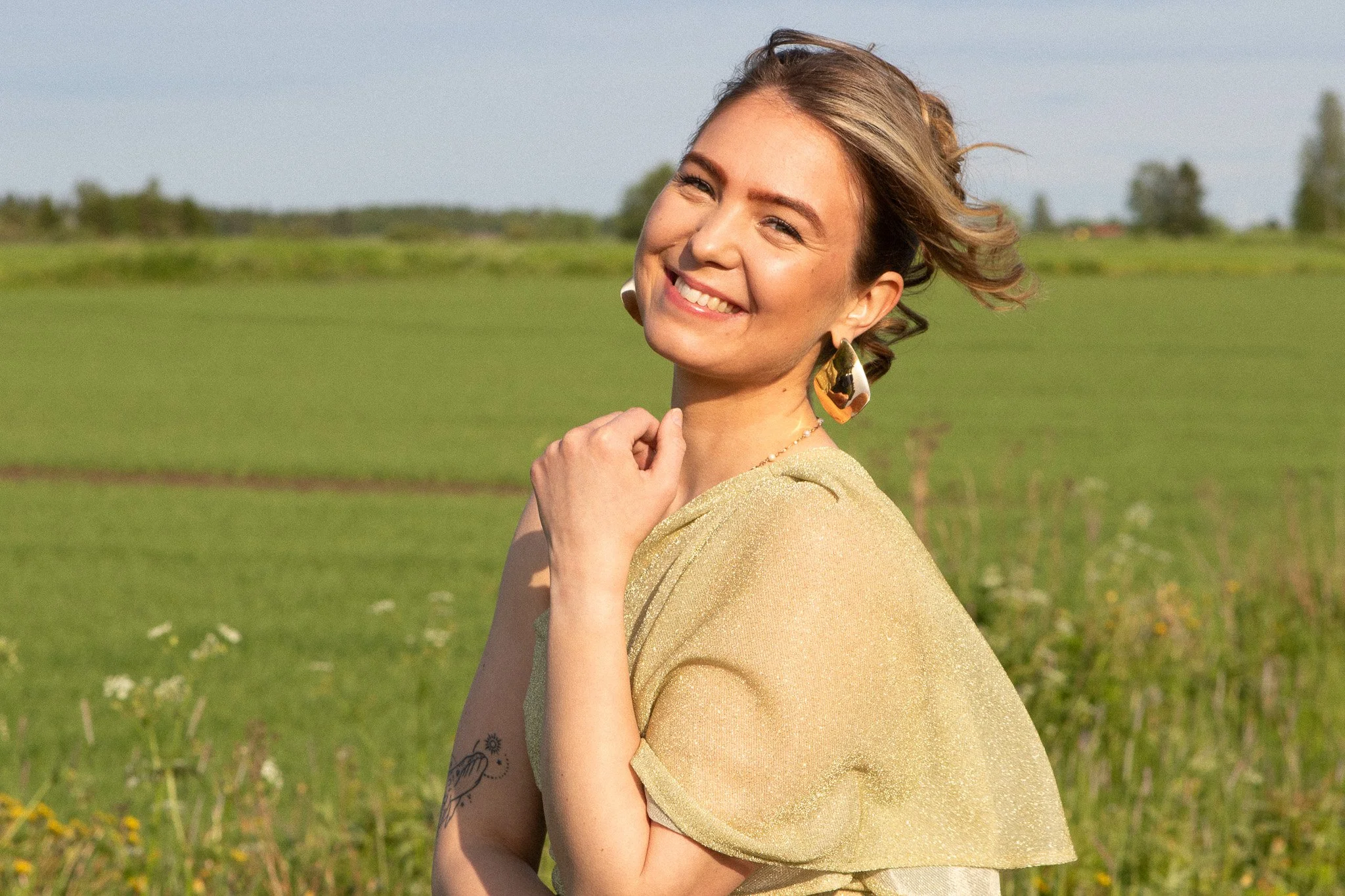 Hymyilevä nainen luonnossa – helposti lähestyttävä henkilöbrändikuvaus pehmeässä ja lämpimässä valossa