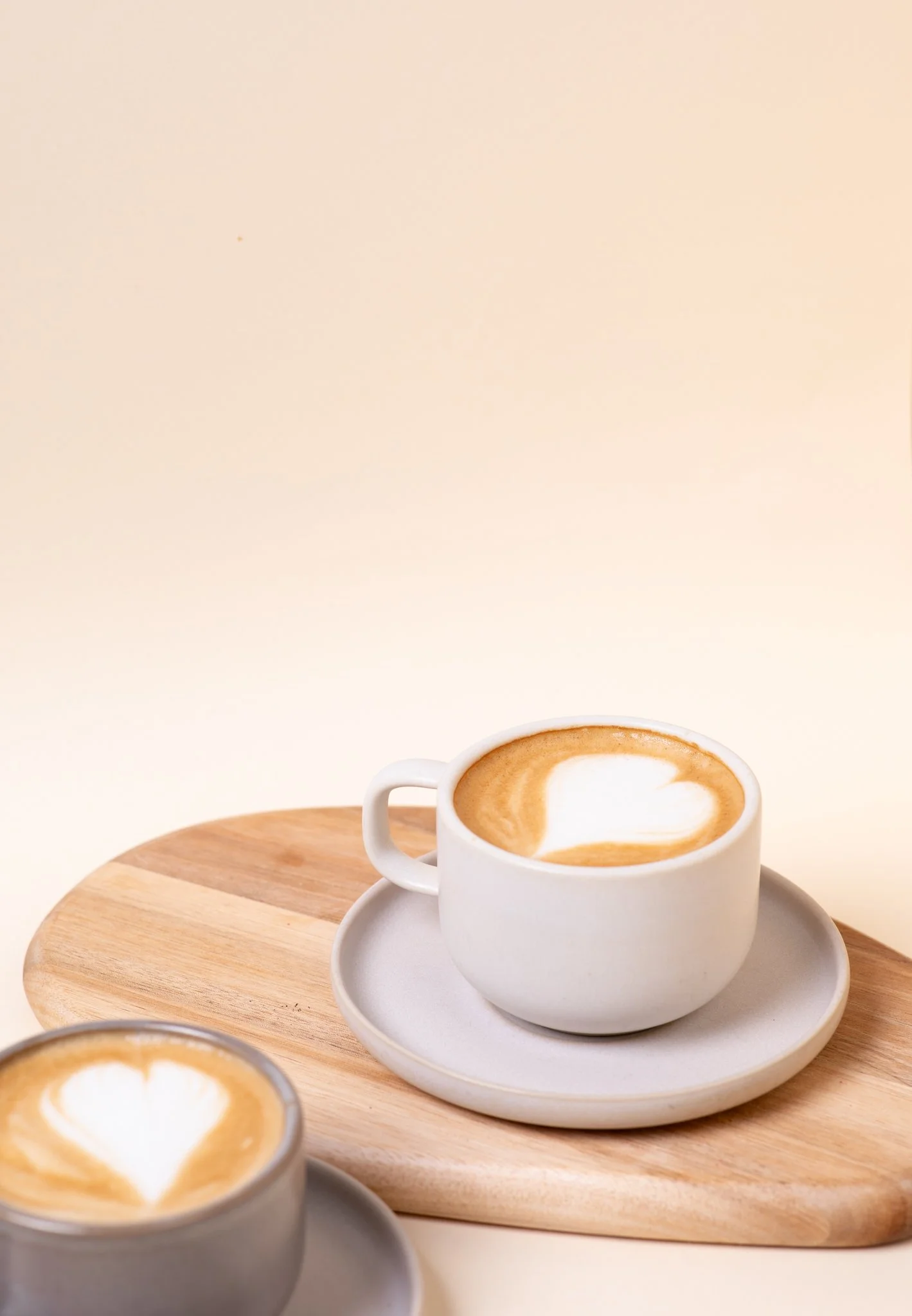 Latte kahvikupissa puualustalla – minimalistinen tuotekuvaus kahvila- ja lifestyle-brändeille