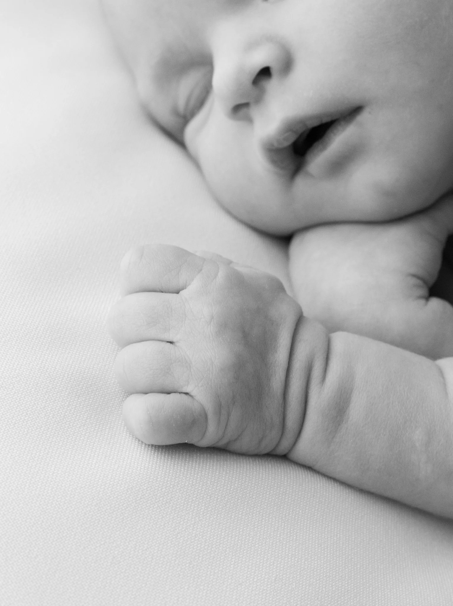 Mustavalkoinen lähikuva vastasyntyneen kädestä – herkkä ja yksityiskohtainen newborn-kuvaus luonnollisessa tyylissä