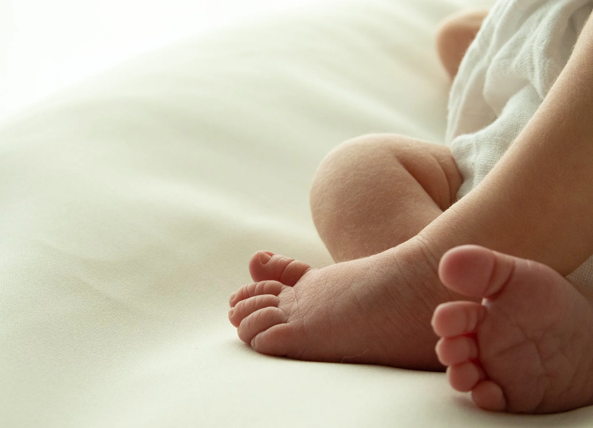 Vastasyntyneen vauvan pienet jalat lähikuvassa – yksityiskohtainen newborn-kuvaus luonnollisessa valossa