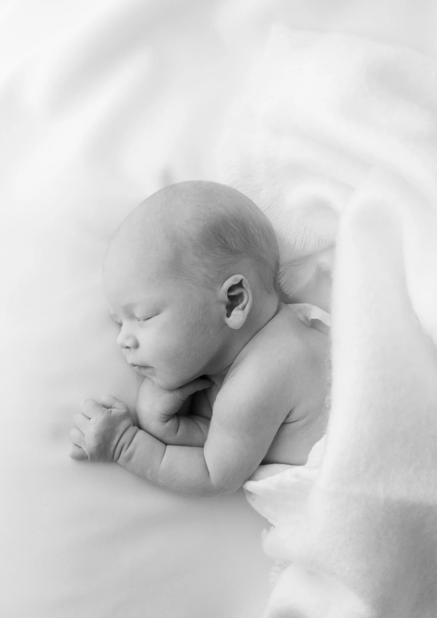 Herkkä mustavalkoinen newborn-kuva vastasyntyneestä – ammattimainen vauva- ja perhekuvaus luonnollisessa tyylissä