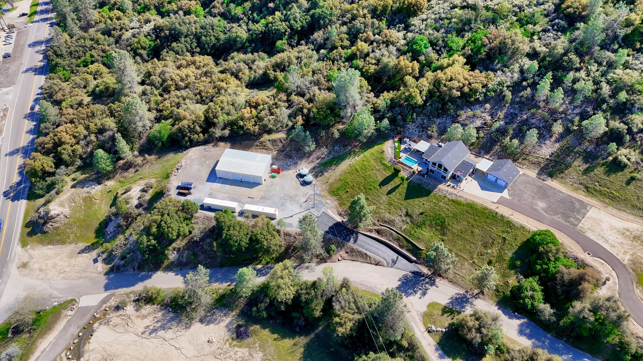 Aerial view of a house with a backyard pool and a large wooded area surrounding it.